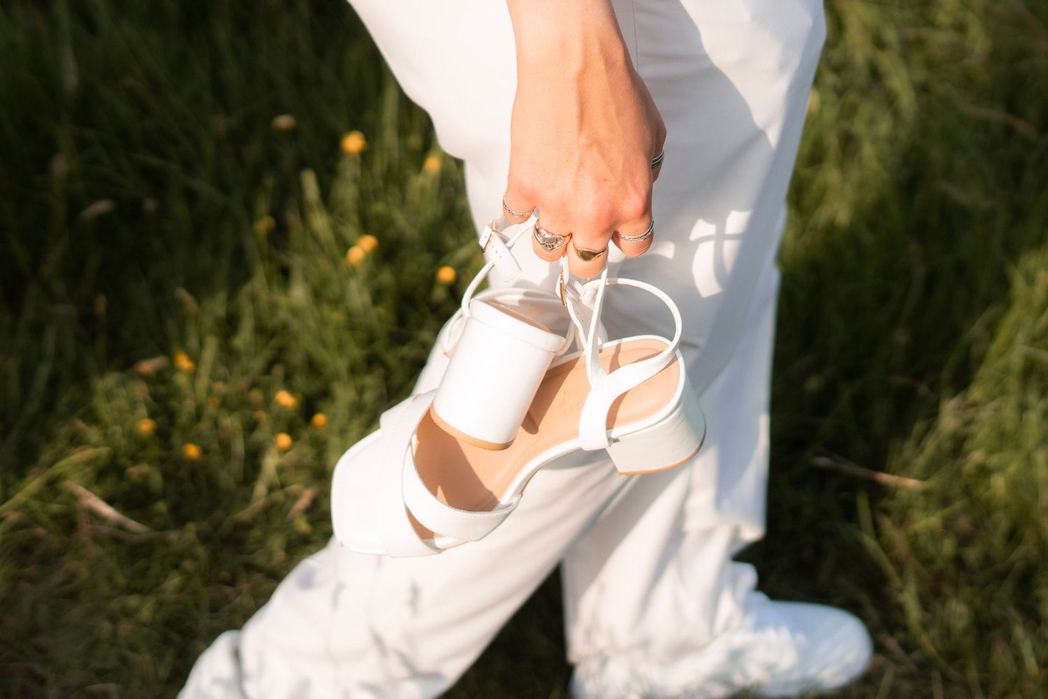 Bride carrying her wife's heels whilst wearing a suit from King and Allen