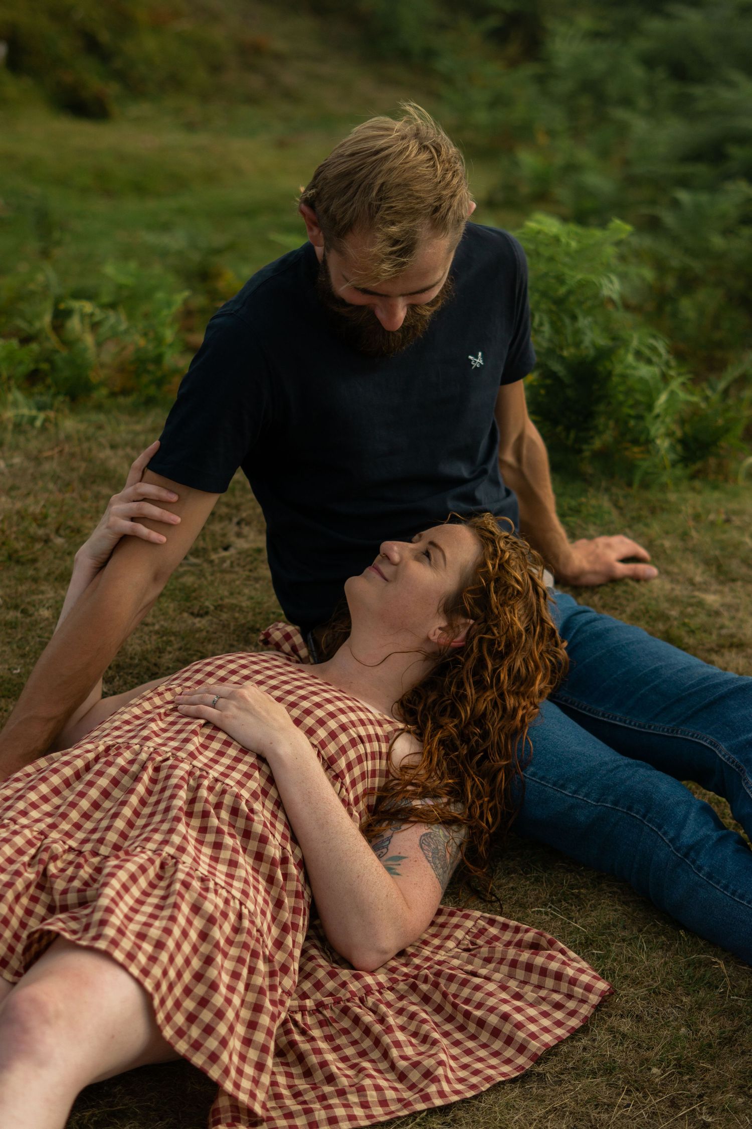 A woman leaning onto her fiancé's lap during an engagement photoshoot on Dartmoor National Park, Devon