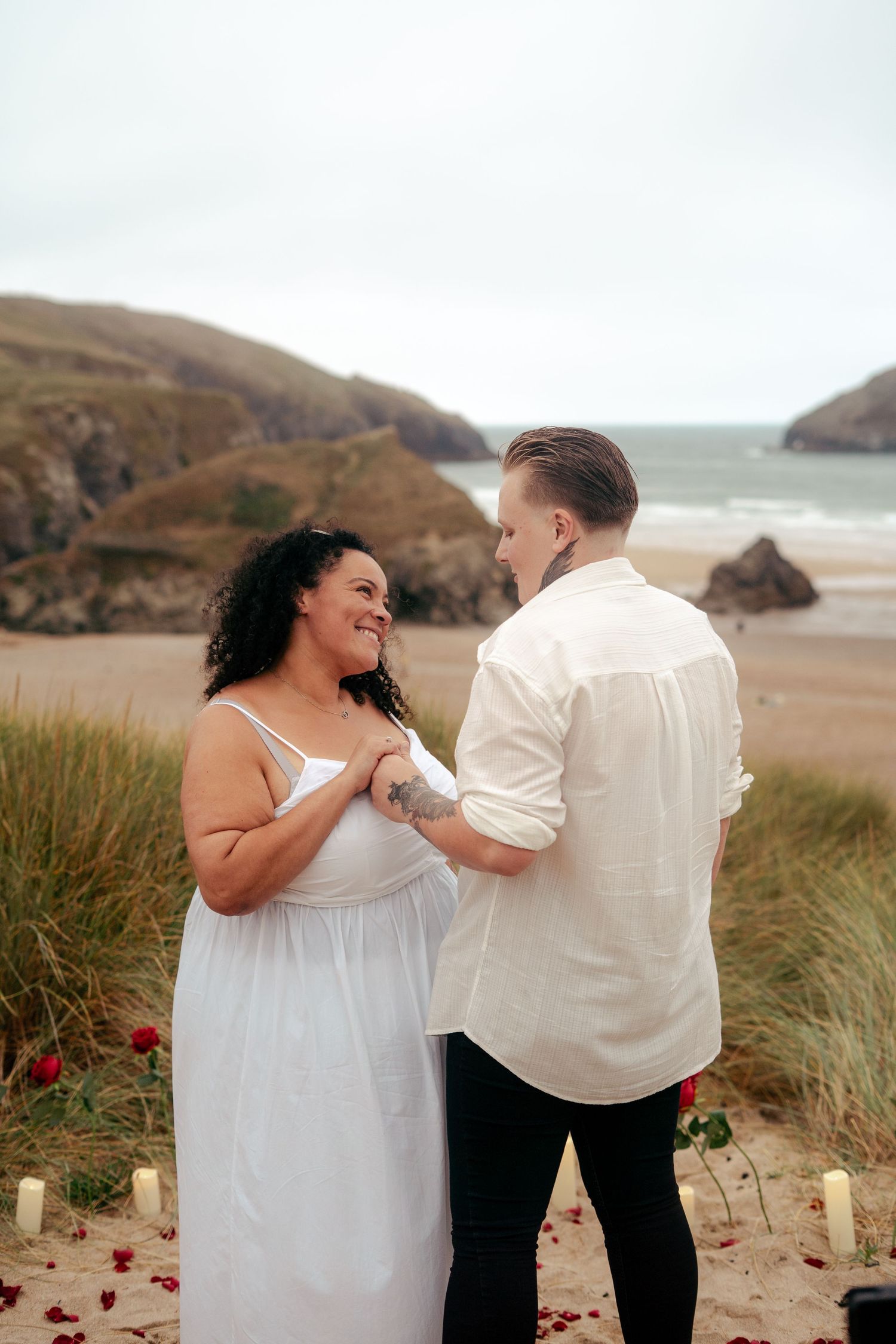 Lesbian proposal on the beach in Cornwall, surrounded by a bed of roses and candles