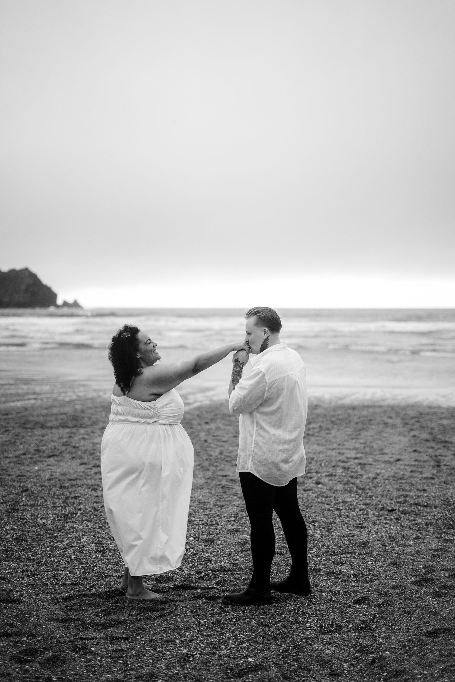 Black and white candid photo of two women kissing on the beach in Cornwall after getting engaged
