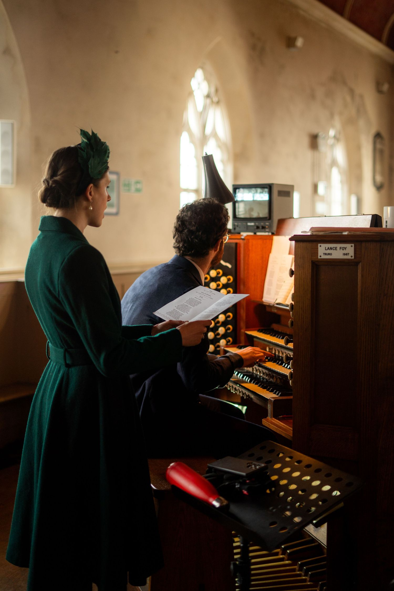 Candid photo of wedding guest playing music during a church ceremony in Penzance, Cornwall