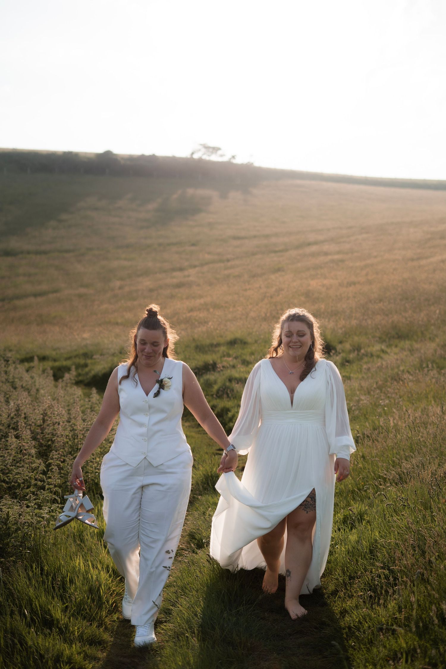 Brides walking along the coast path near Lantic Bay and Lantivet National Trust after their wedding at Tredudwell Manor