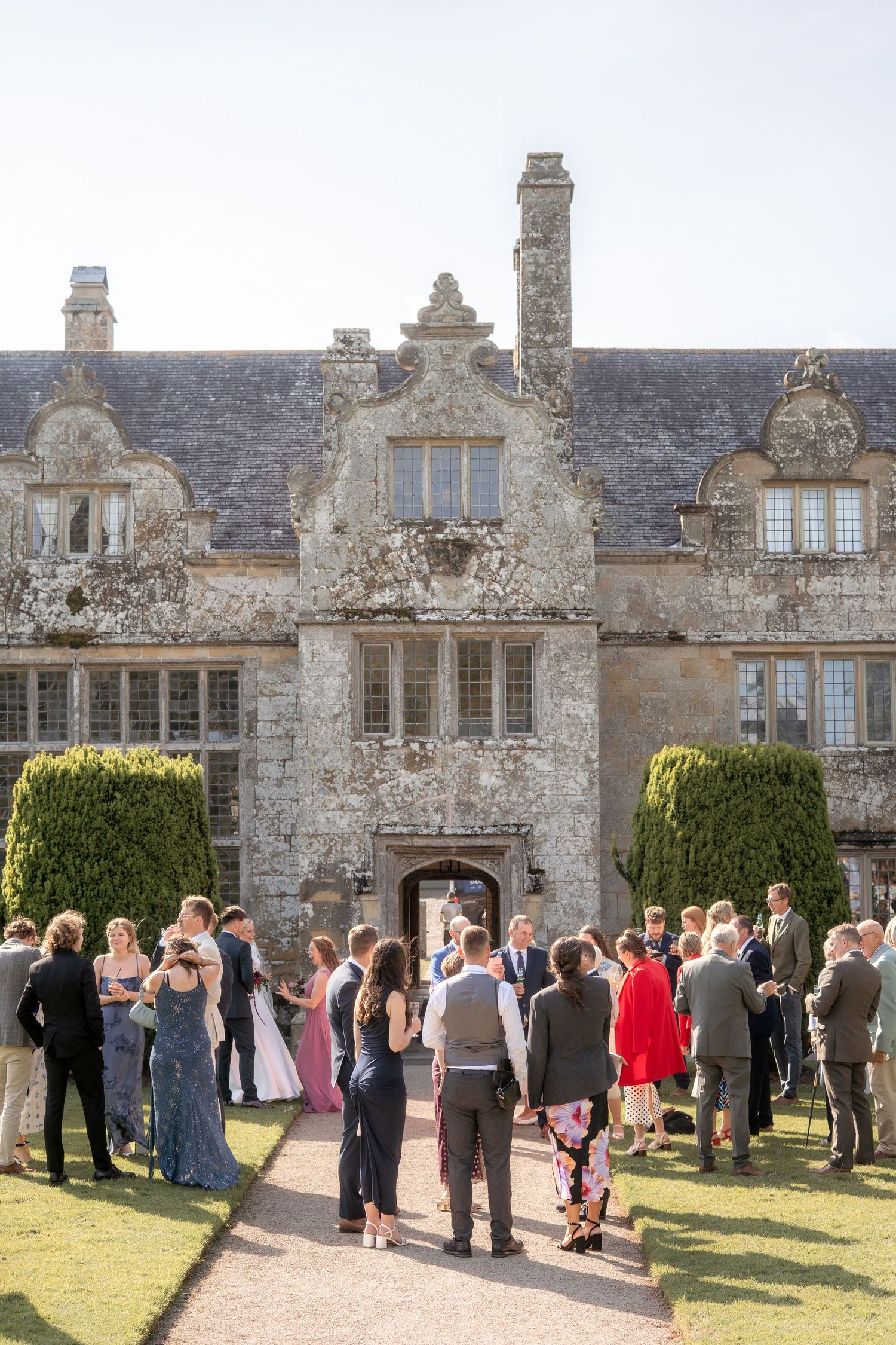 Wedding guests gathering outside Trerice National Trust, captured by Newquay wedding photographer