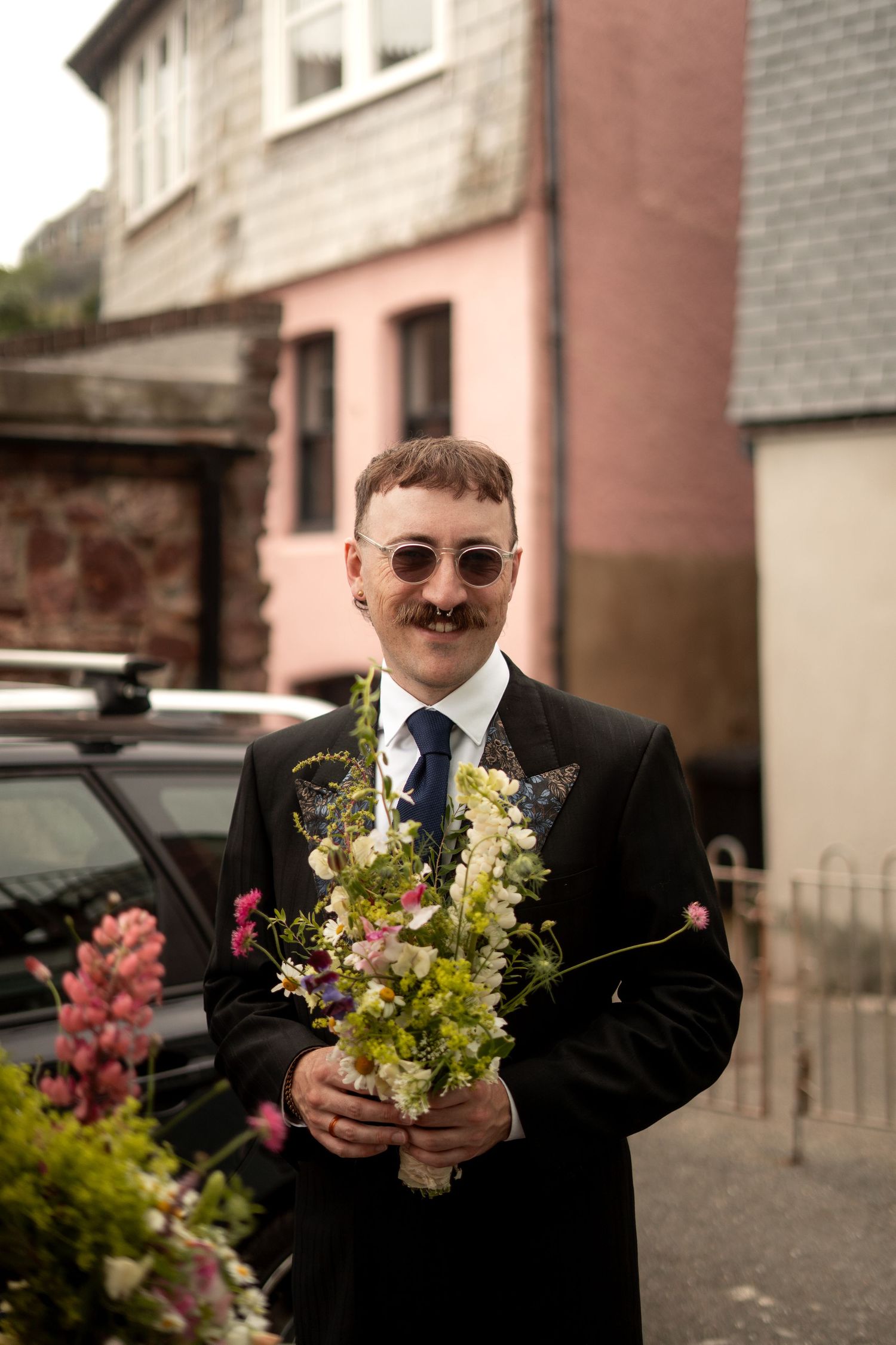Male bridesmaid smiling with his bouquet before walking to the wedding venue