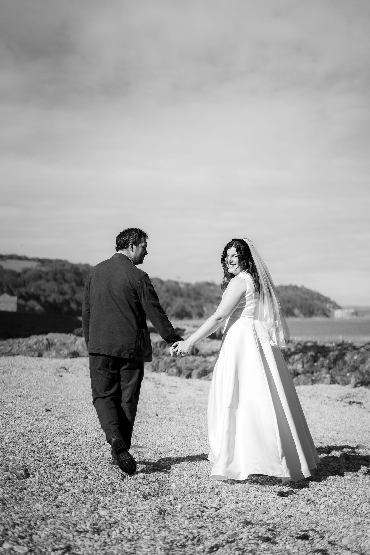 Black and white documentary style photo of bride and groom on the beach in Cornwall