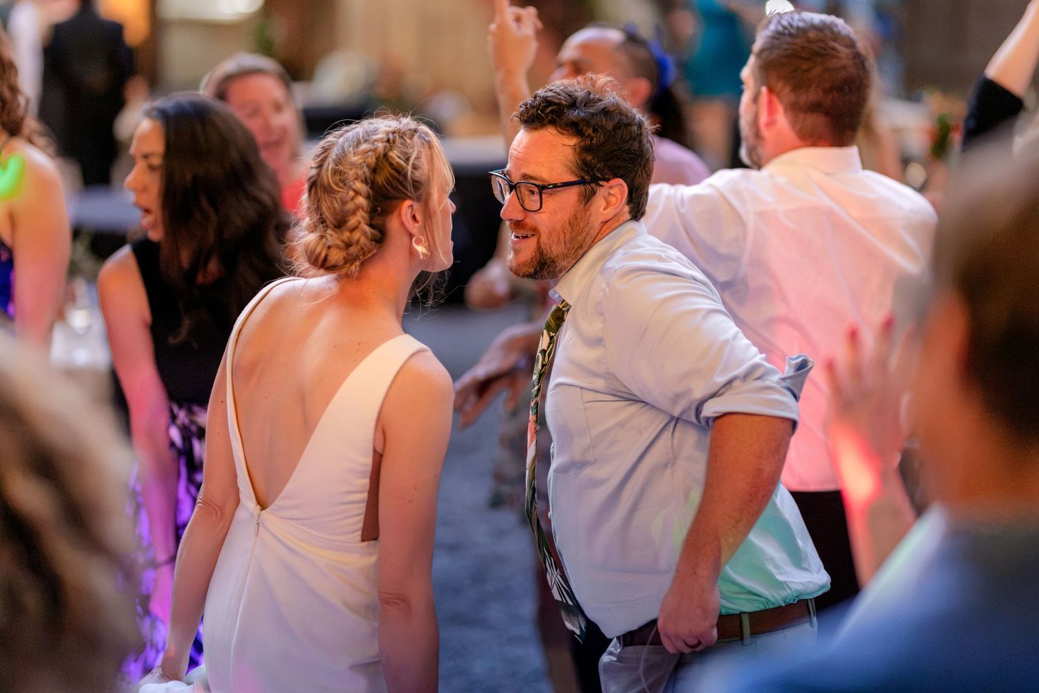 Bride and groom share intimate dance moment surrounded by guests at wedding reception.