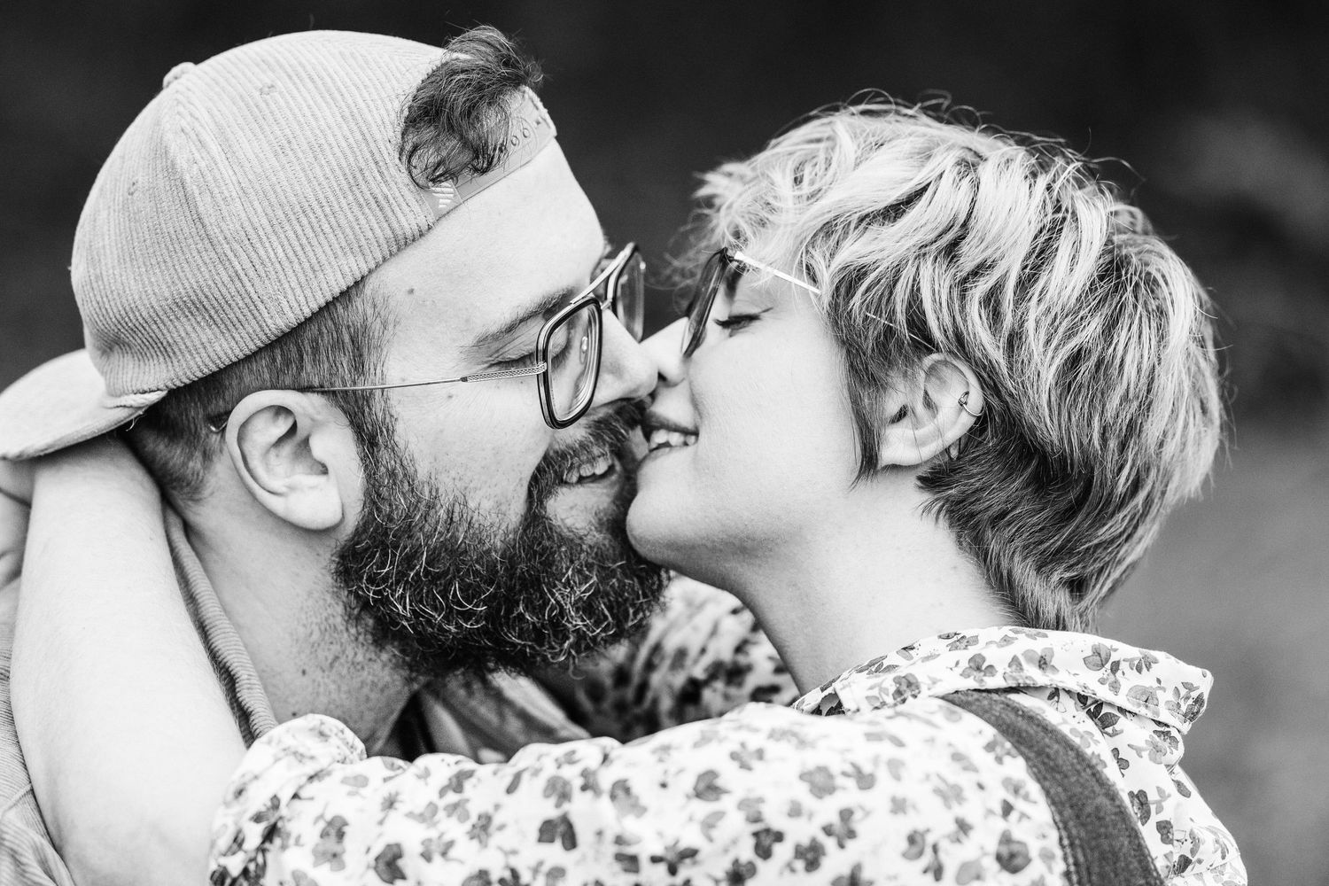 A black and white collage of intimate romantic moments between a couple wearing casual attire and glasses.