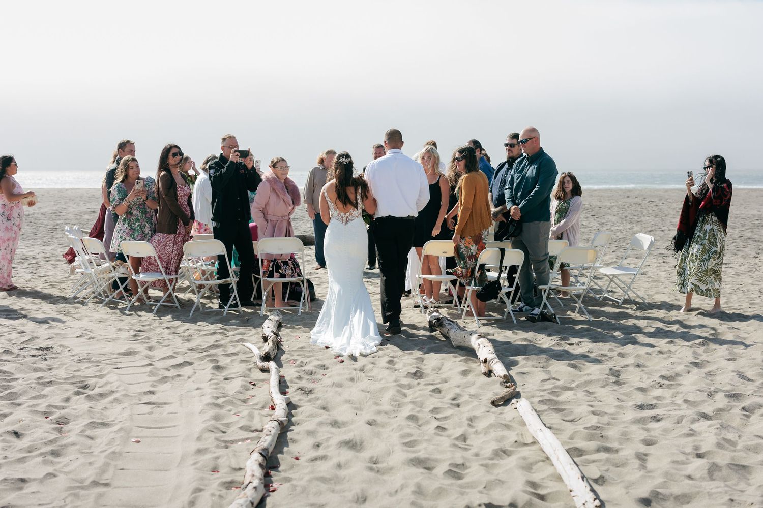 A beach wedding ceremony setup with guests gathered on the sand.