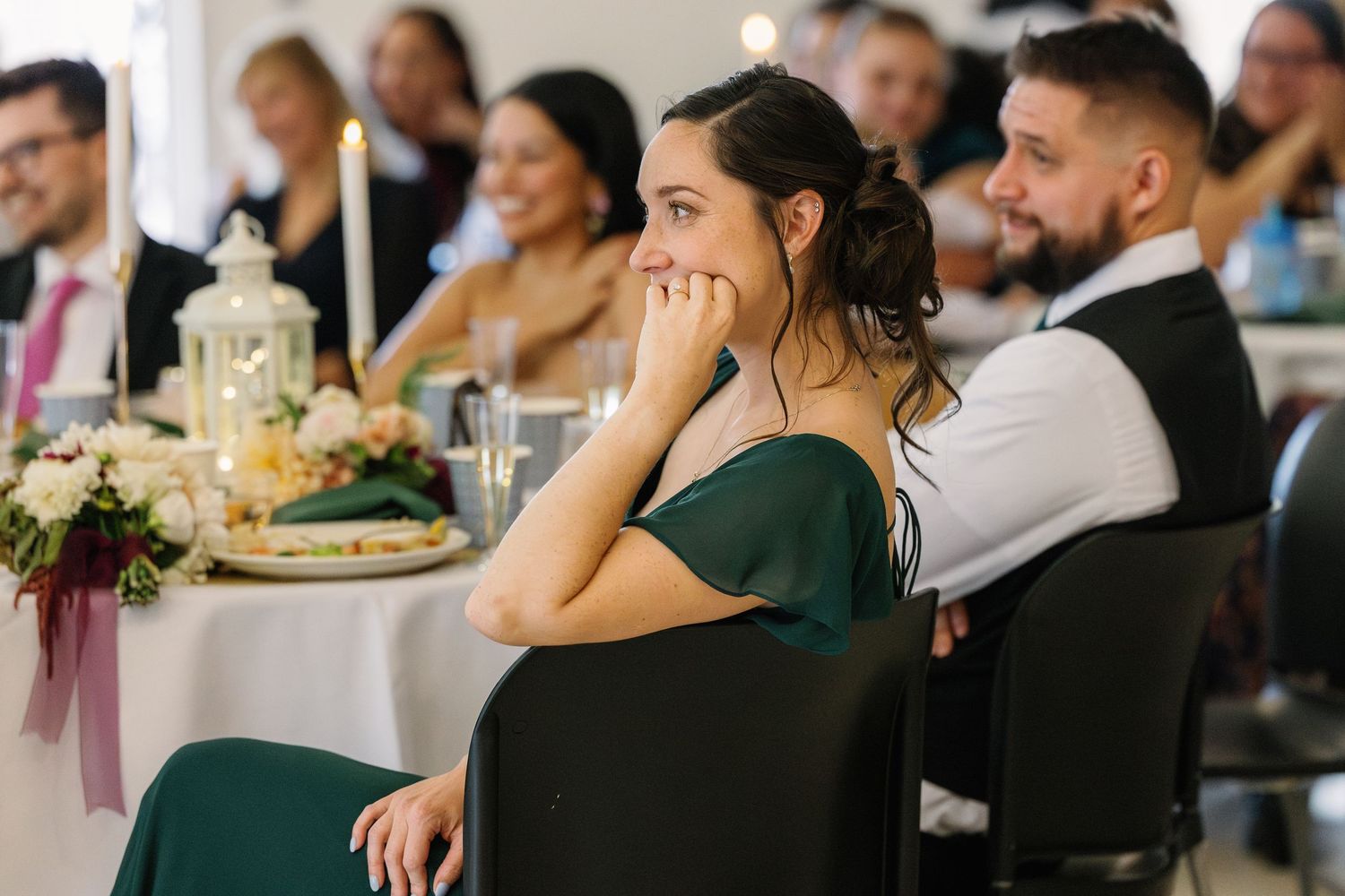 Wedding reception guests in formal attire seated at decorated tables during celebration.