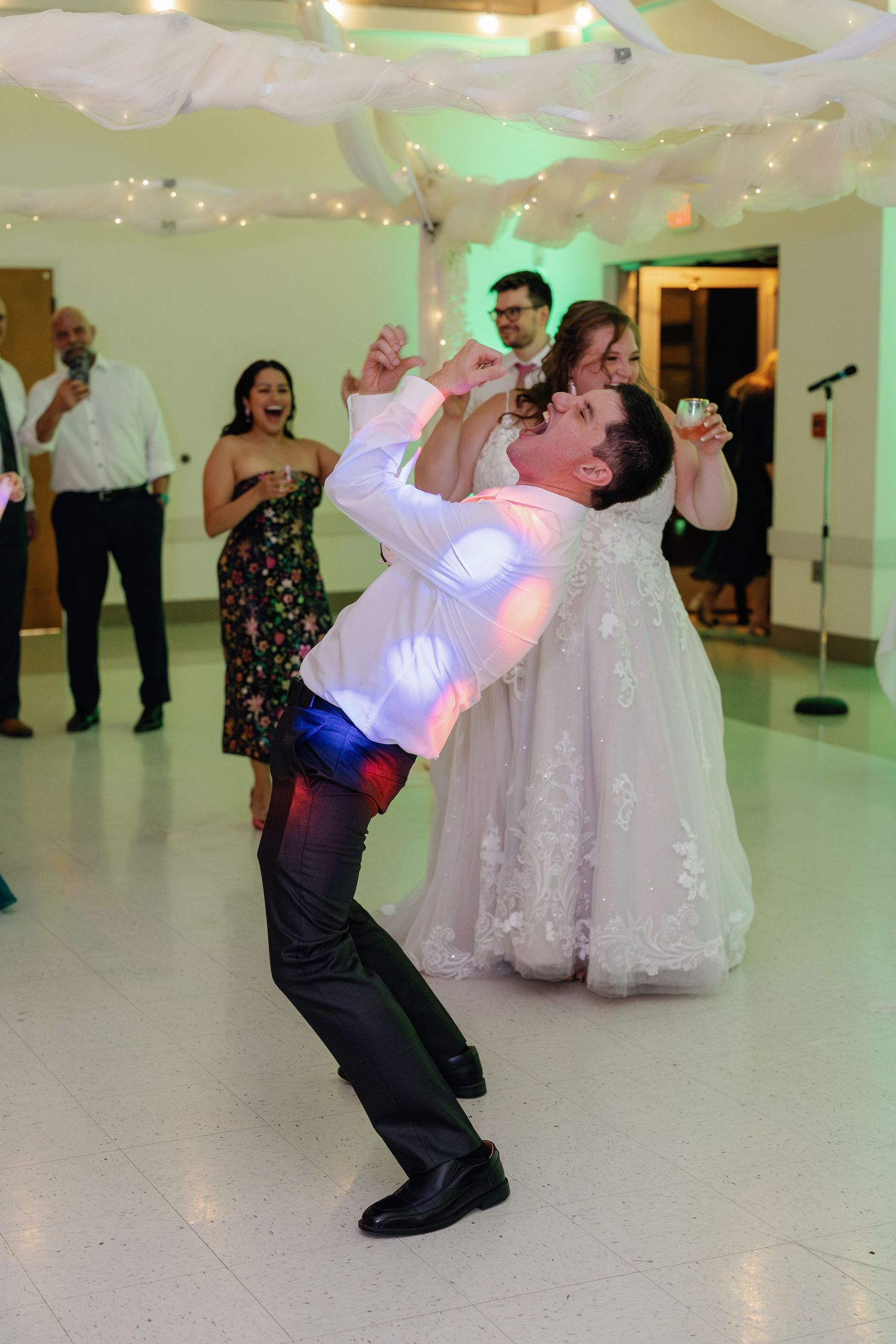 A guest performs an energetic dance move during a lively wedding reception.