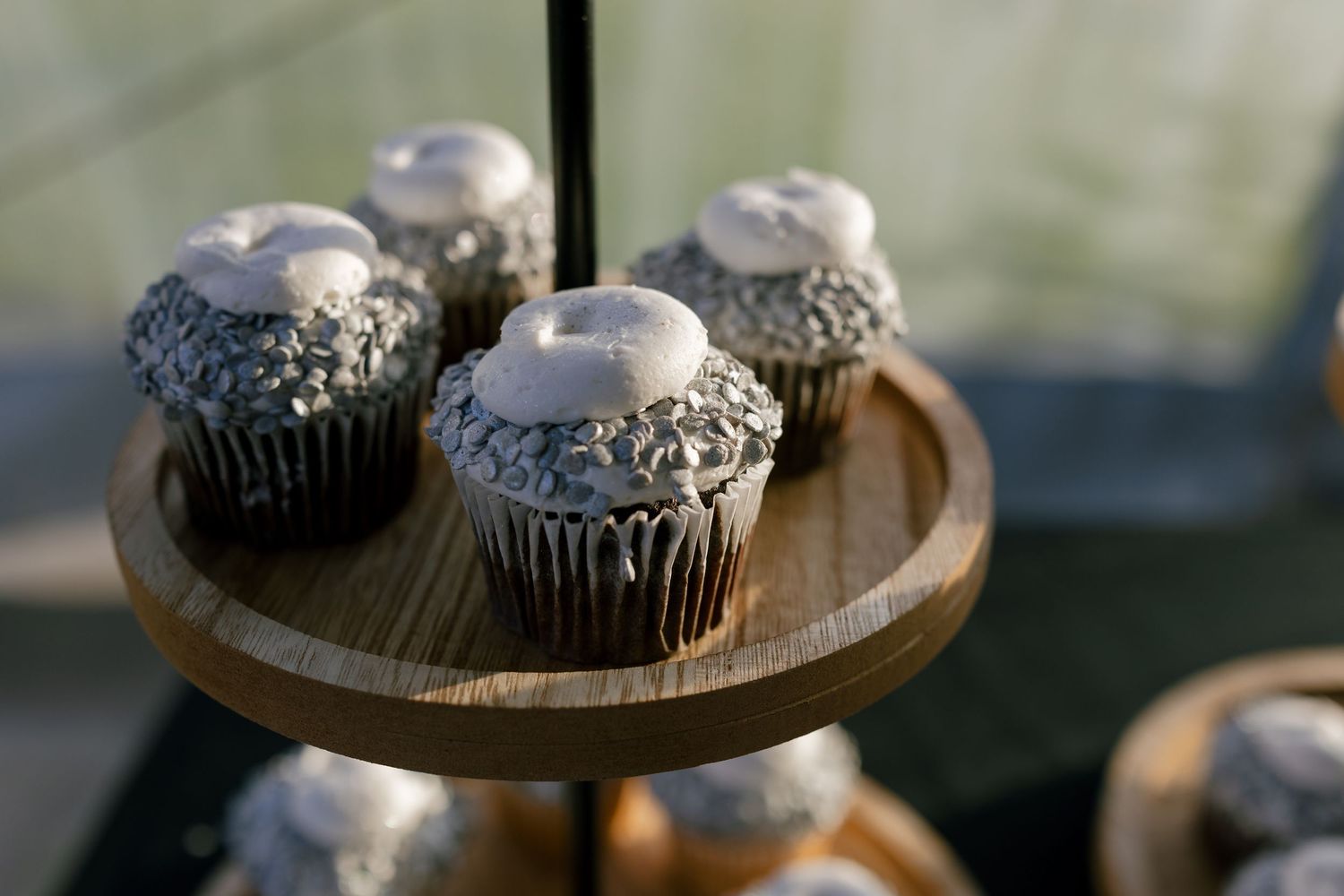 Black and silver decorated cupcakes displayed on wooden serving platters.