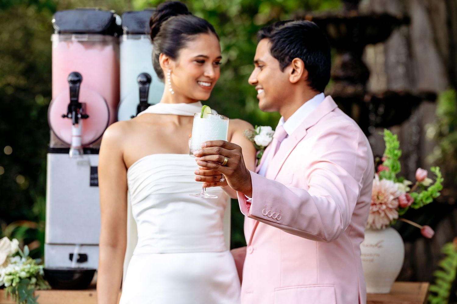 A couple shares a romantic dance moment during their wedding reception in an outdoor garden setting.