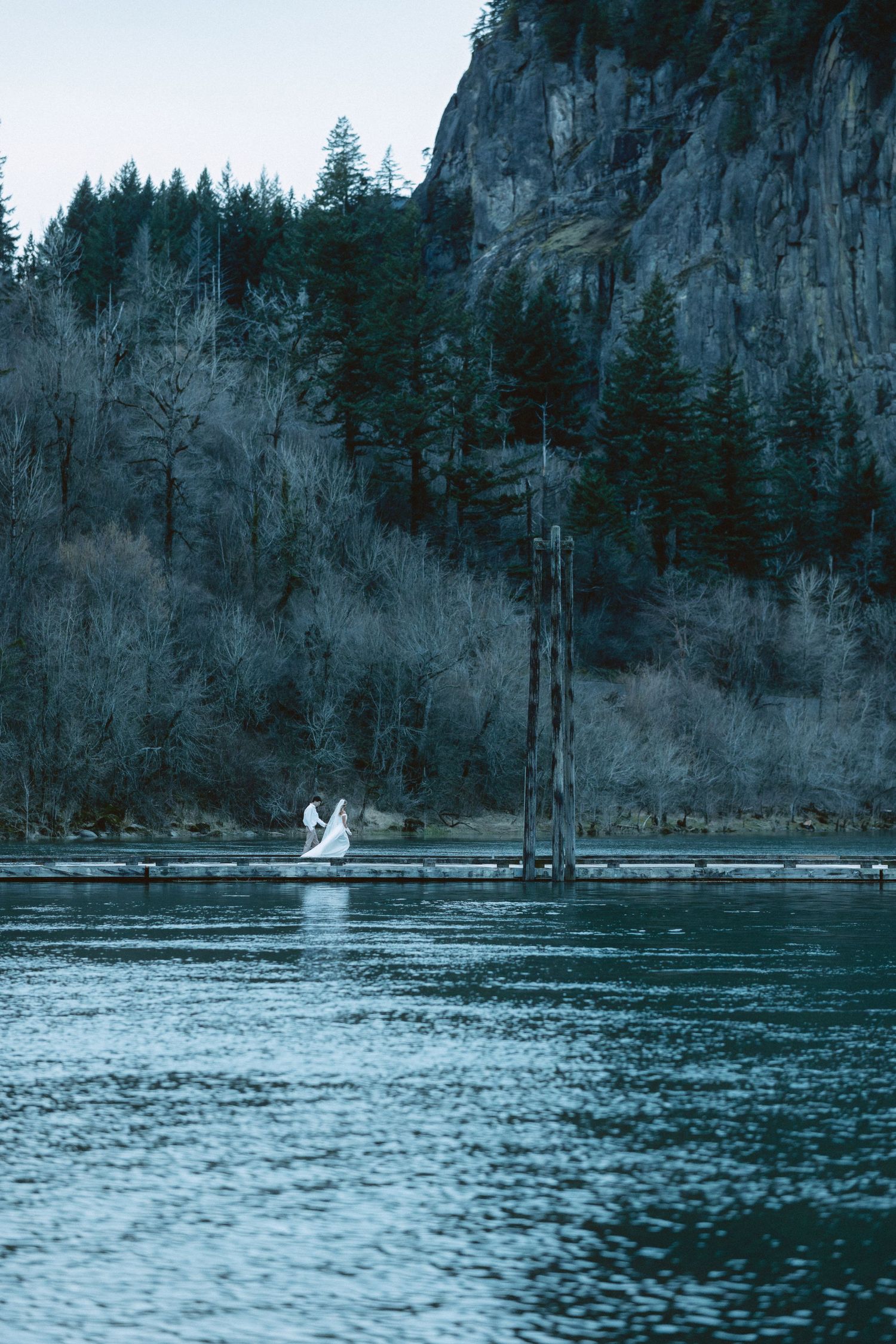 A tranquil lake surrounded by evergreen forests and rocky cliffs with a small boat visible in the distance.