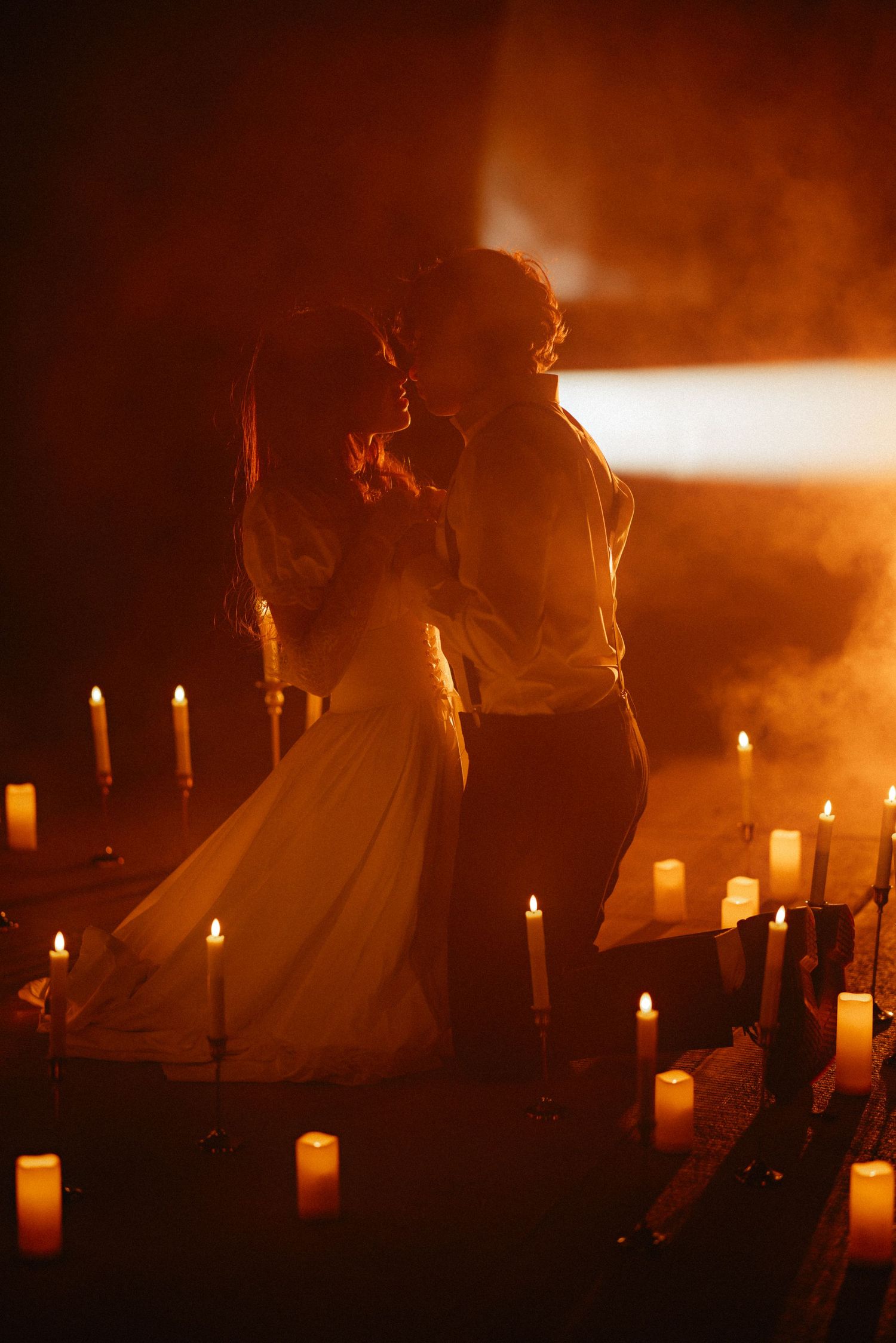 Silhouettes move through a candlelit space creating dramatic shadows and warm lighting effects.