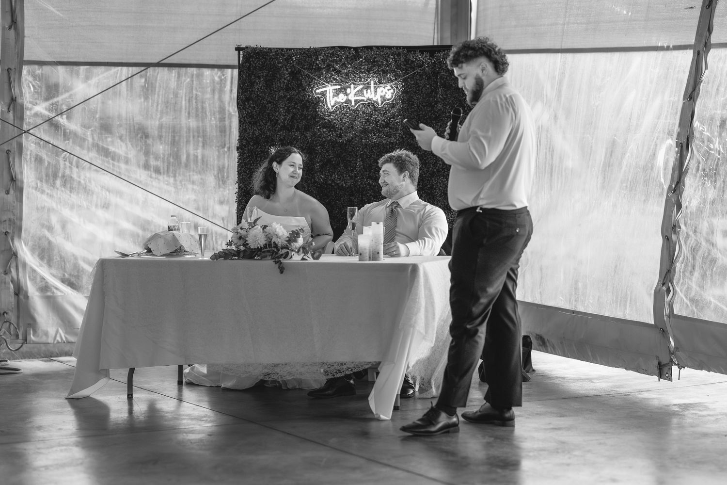 Wedding guests dance and celebrate under a white reception tent.