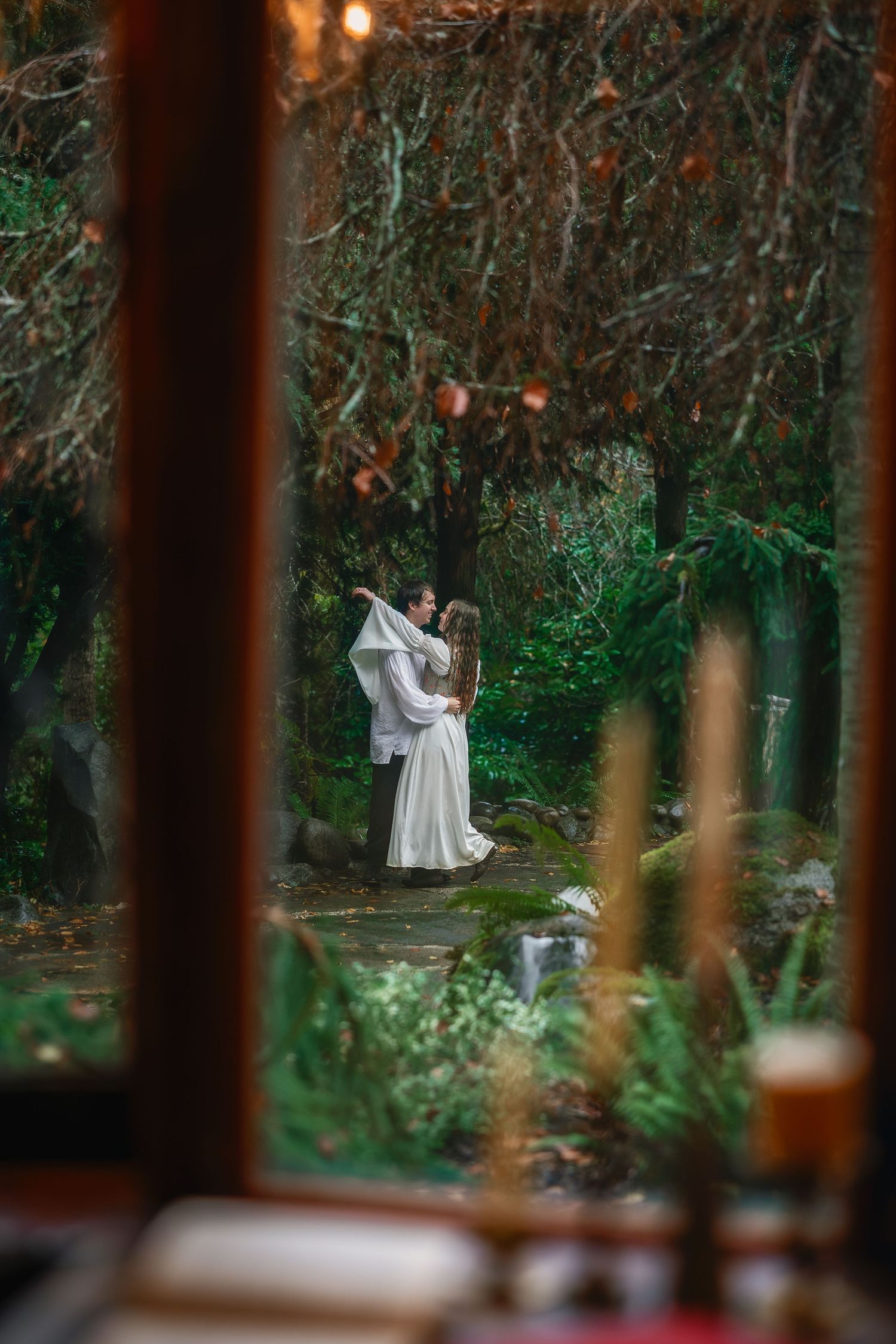 A romantic scene viewed through tree trunks in a wooded setting with natural lighting.