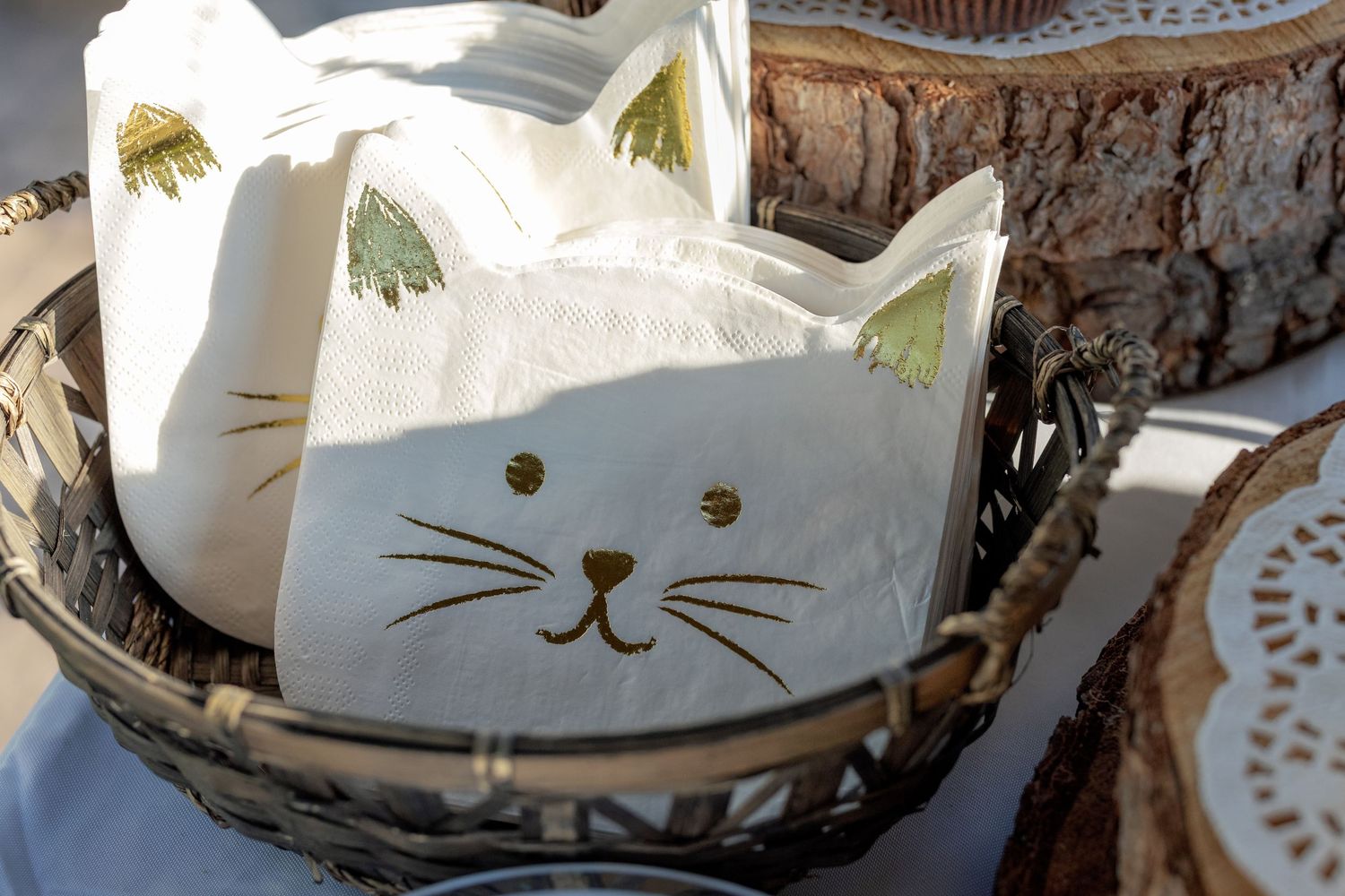 White ceramic cat-shaped bowls or containers arranged in a rustic basket display.