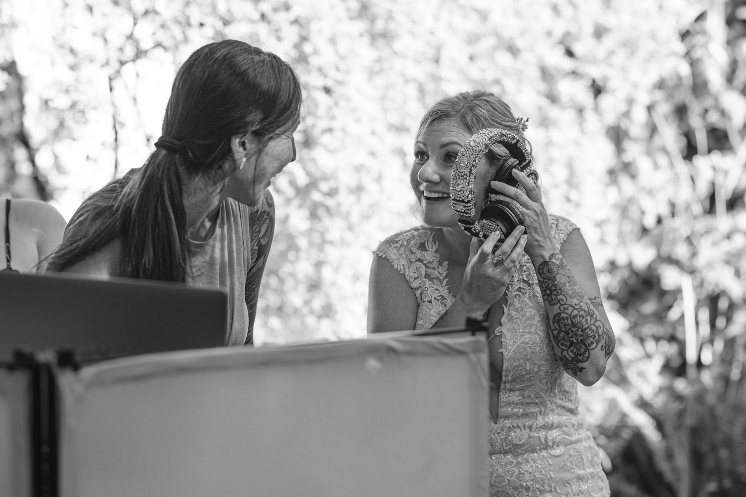 Black and white candid wedding photograph showing a heartfelt moment between two people in an outdoor setting.