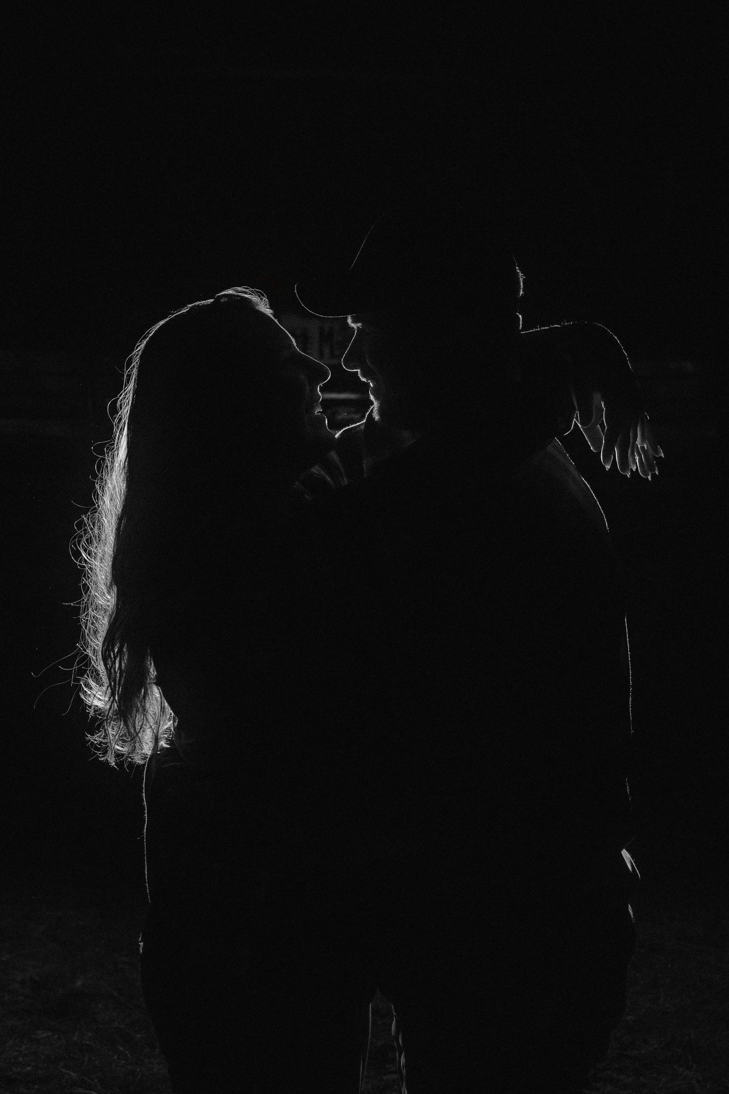 Dramatic silhouettes against black background with ethereal white smoke or light effects.