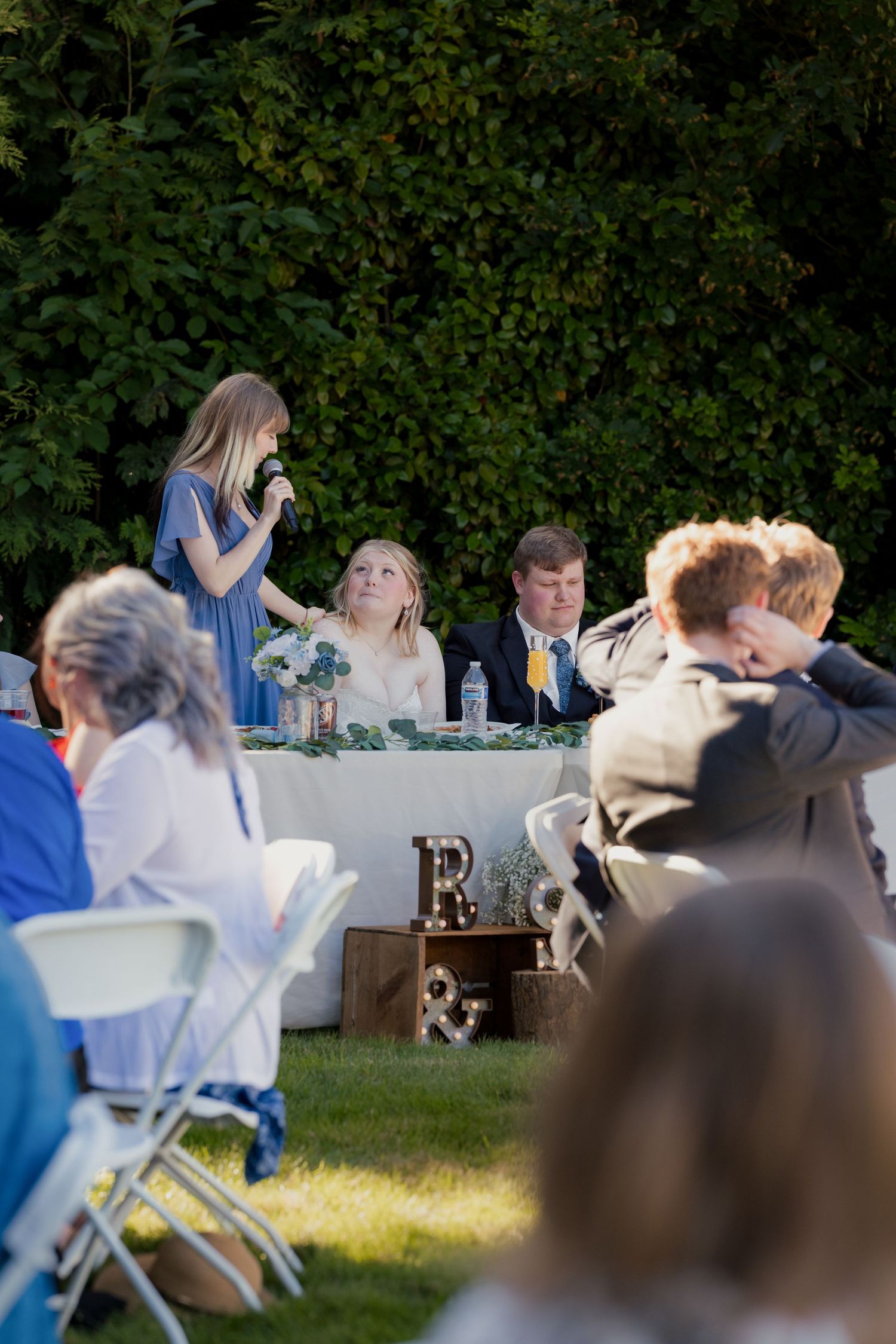 Bridesmaid gives a heartfelt speech at an outdoor wedding reception.