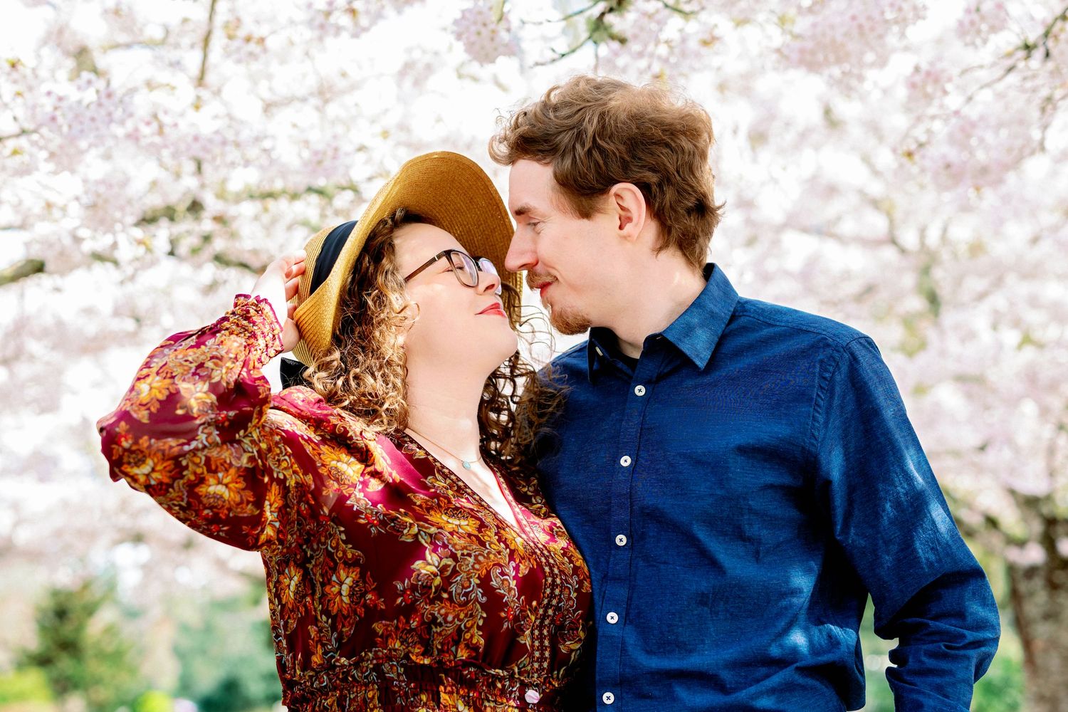 A couple shares romantic moments under blooming cherry blossoms in a spring garden setting.