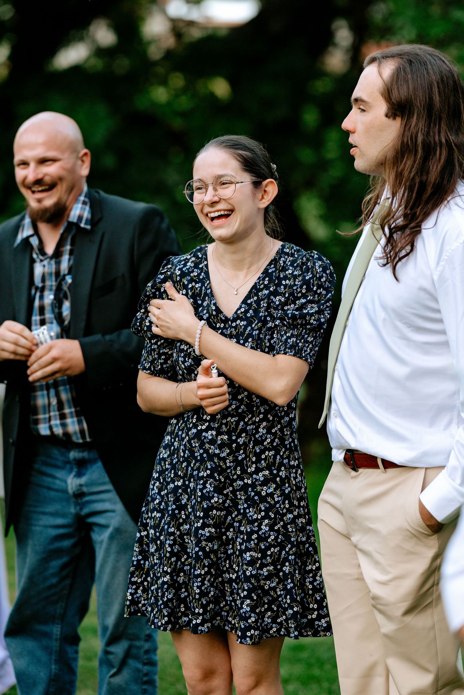 Wedding guests laugh and celebrate together outdoors during a joyful garden wedding reception.