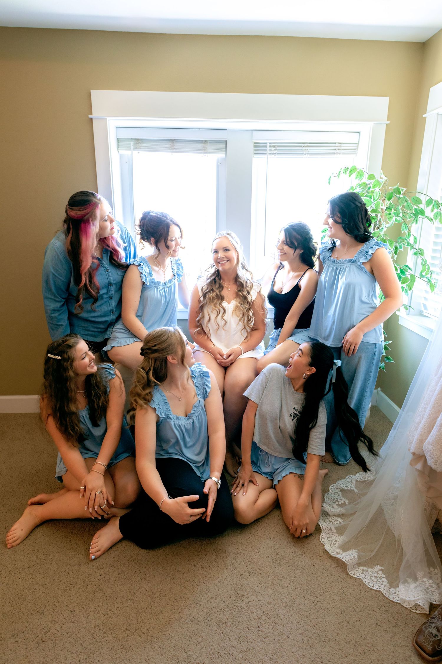 Bride and bridesmaids in blue pajamas gather together laughing before the wedding ceremony.