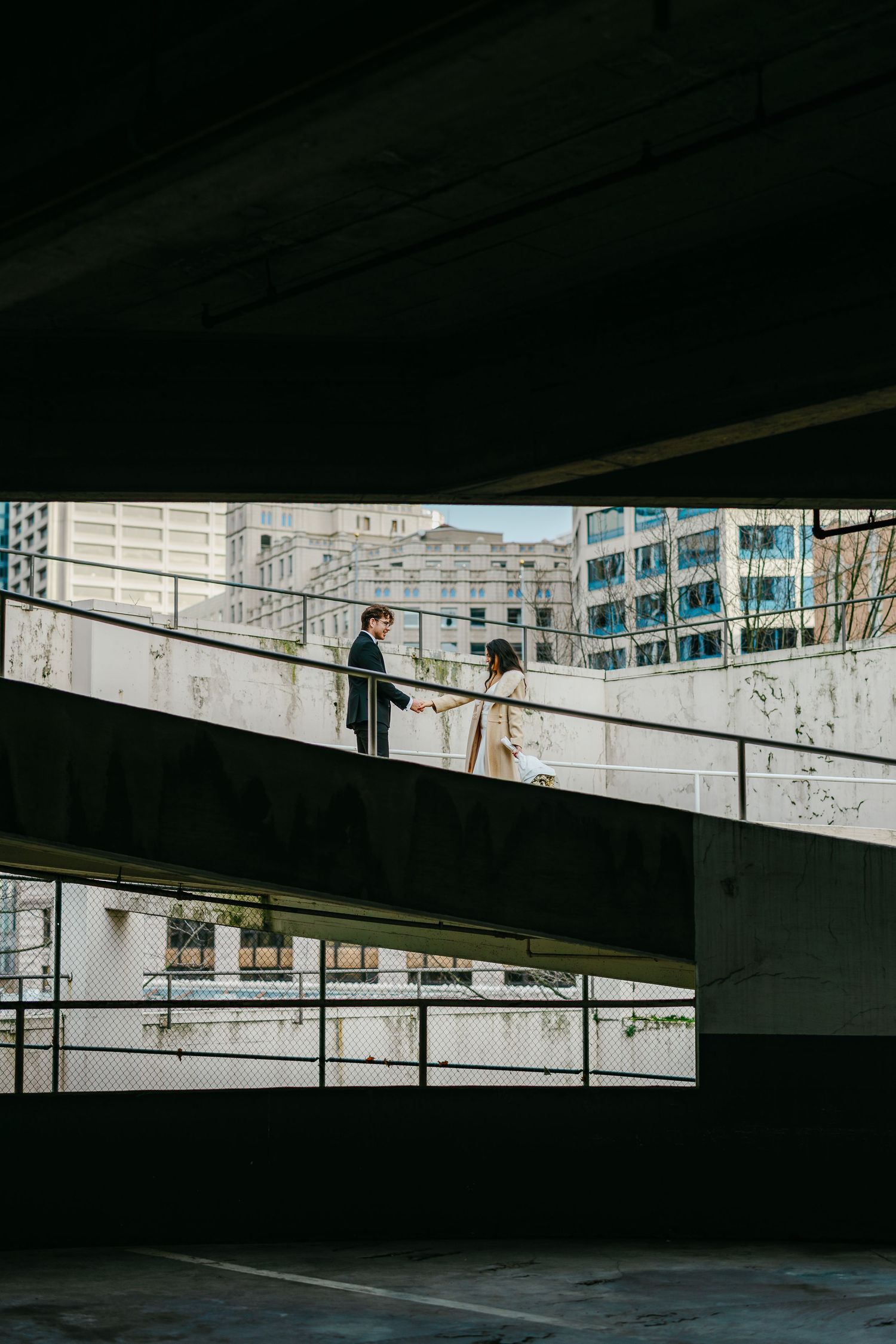 A dark and moody parking garage interior with diagonal lines and concrete architecture creating geometric patterns.