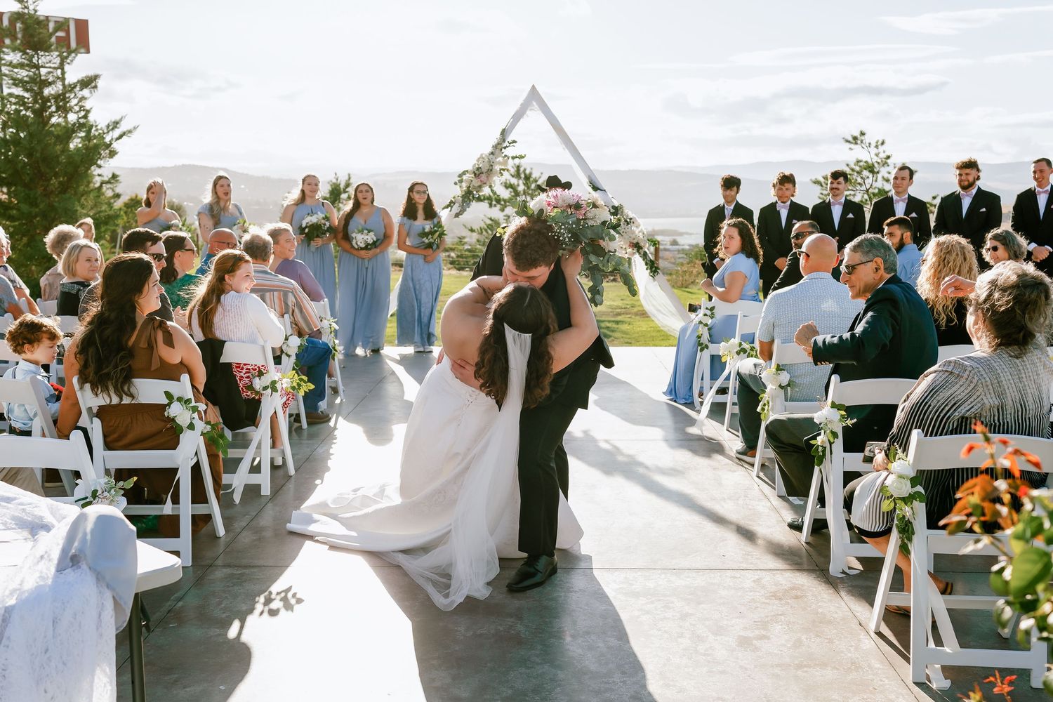 Guests seated at outdoor reception tables during a sunset celebration with mountain views.