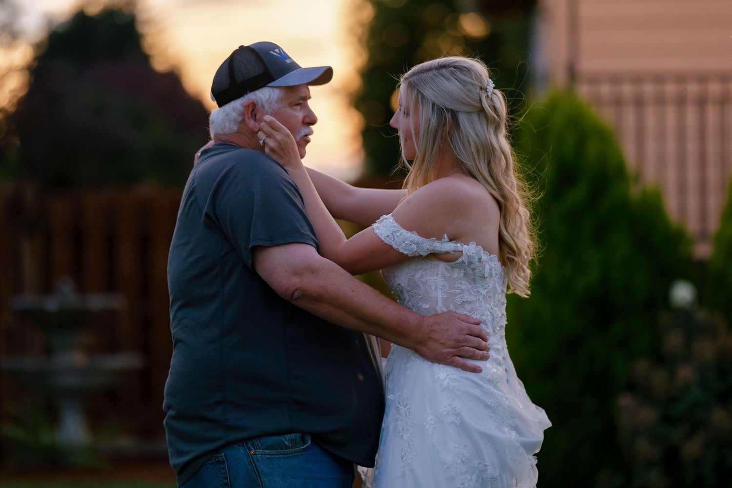 Romantic sunset dance moment at an outdoor wedding reception.