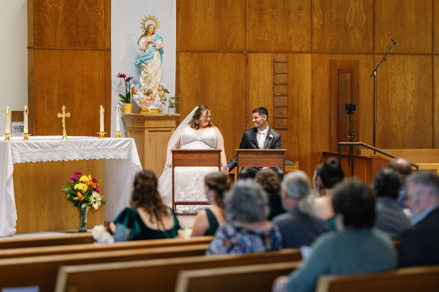 Interior view of a traditional church sanctuary with wooden walls and pews filled with wedding guests.