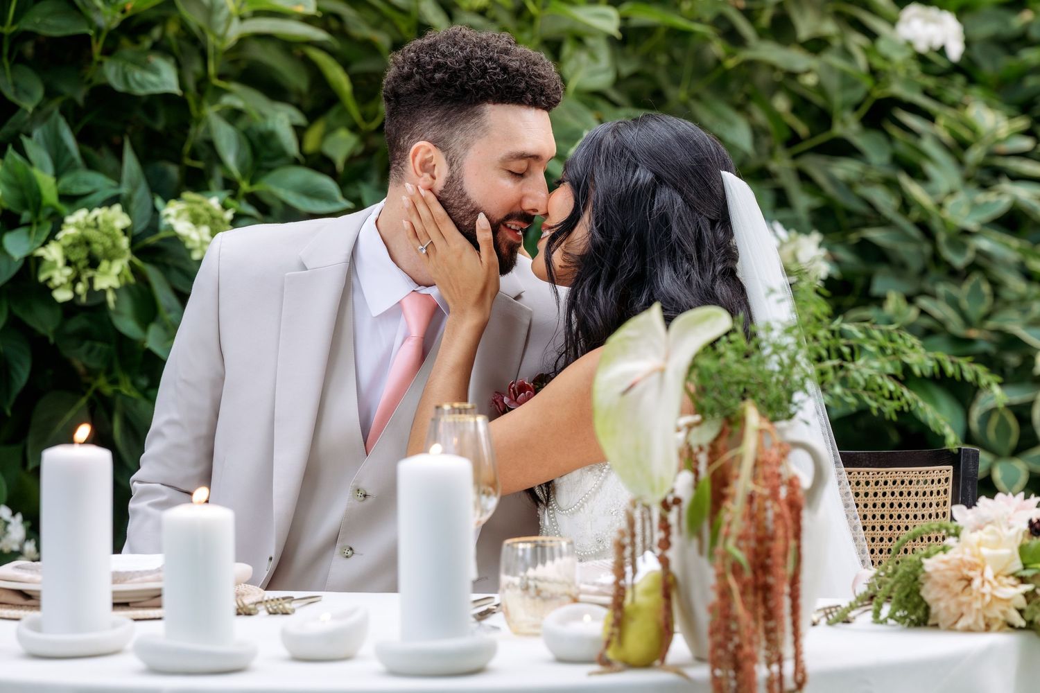 Romantic outdoor wedding reception scene with white candles and greenery decorations.