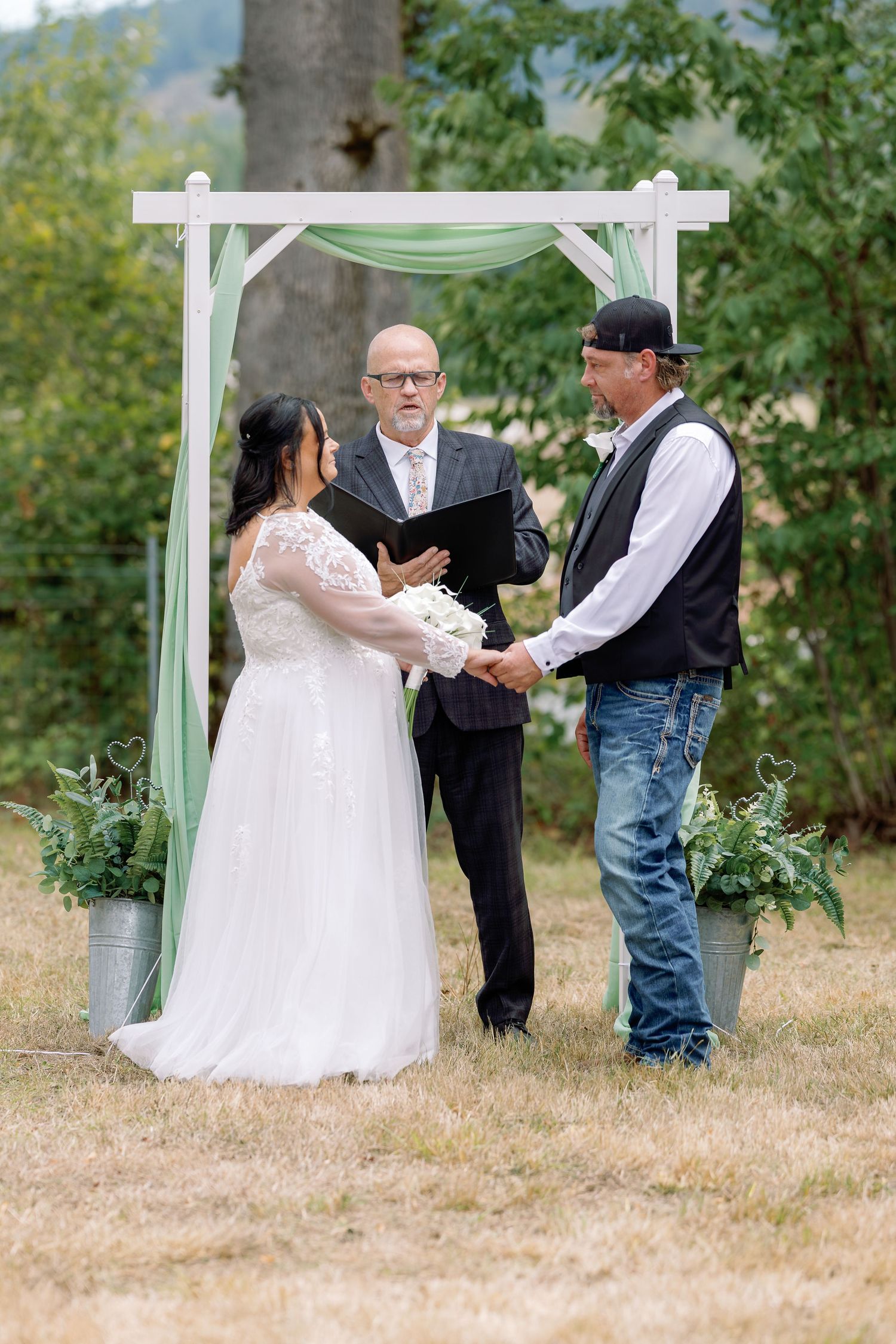 A series of outdoor wedding ceremony photos showing a couple and officiant under a white arbor in a natural setting.