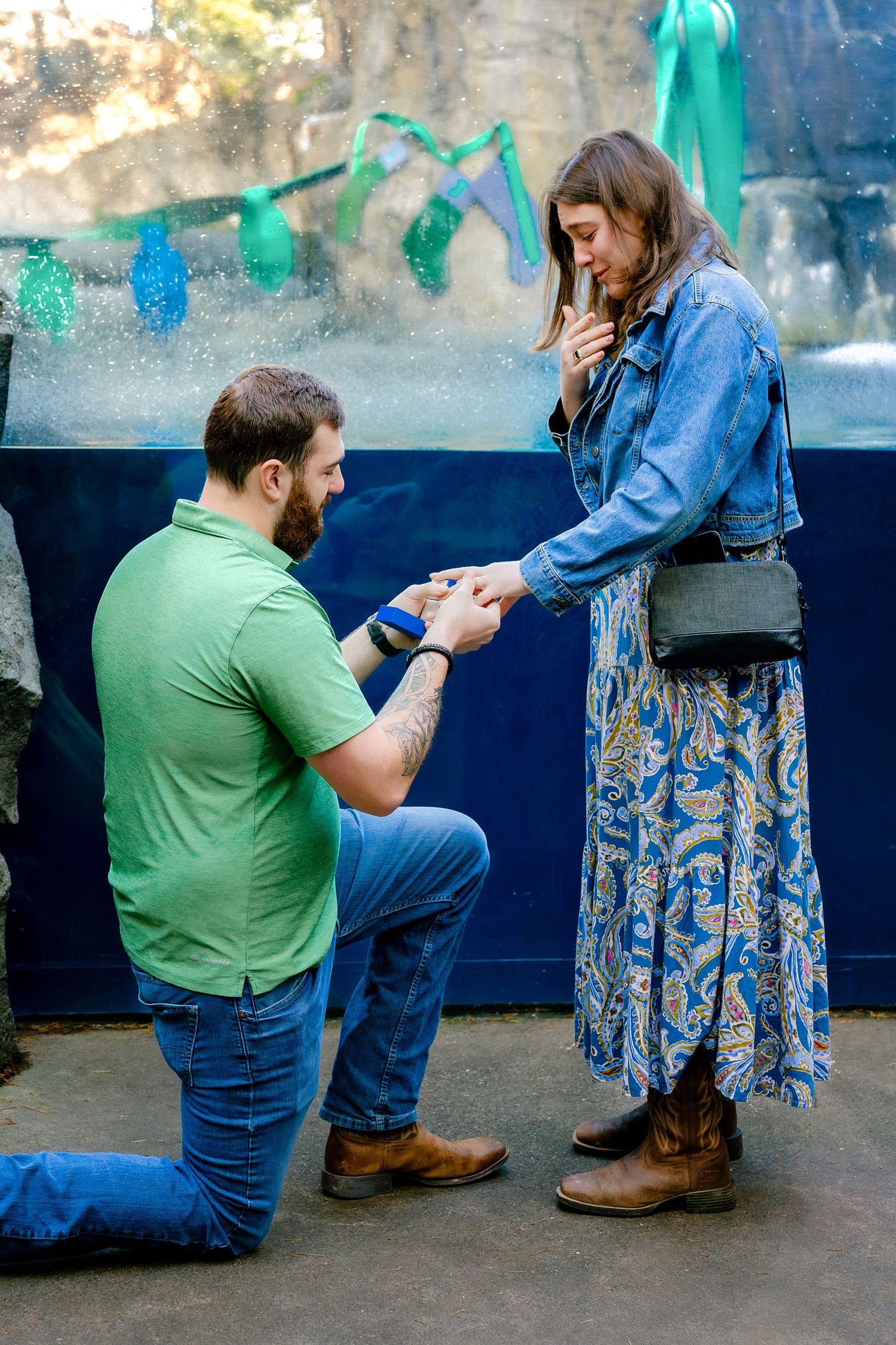 A romantic proposal scene with teal decorations in an aquarium setting.
