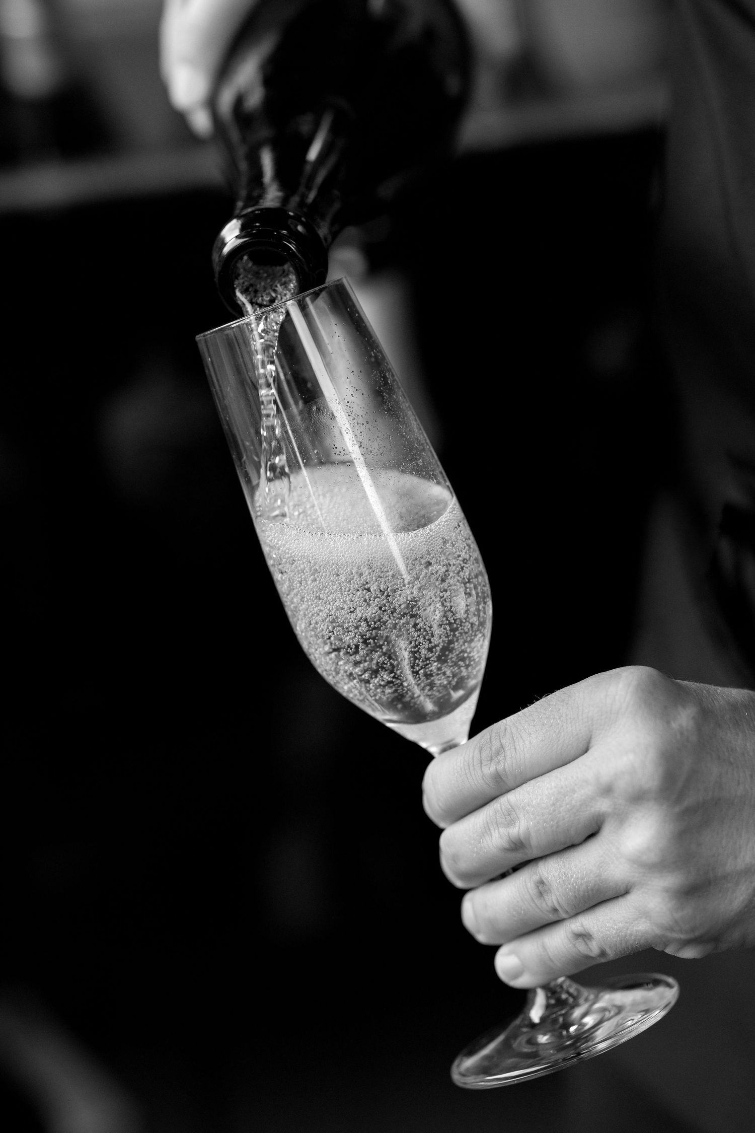 Champagne being poured into elegant flutes in a black and white sequence.
