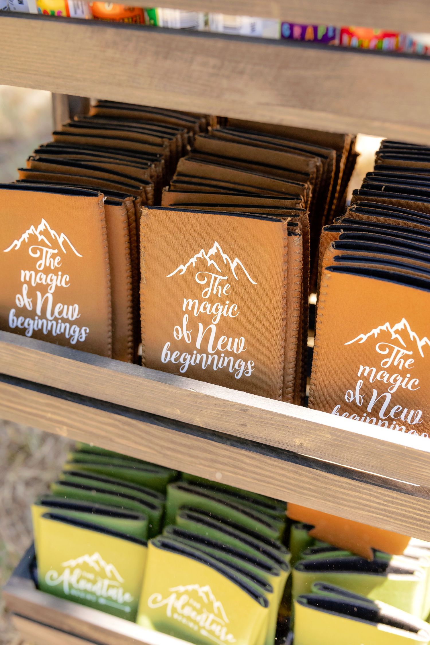 Rustic wooden shelf displaying orange journals with white mountain graphic and The Magic of New Beginnings text.