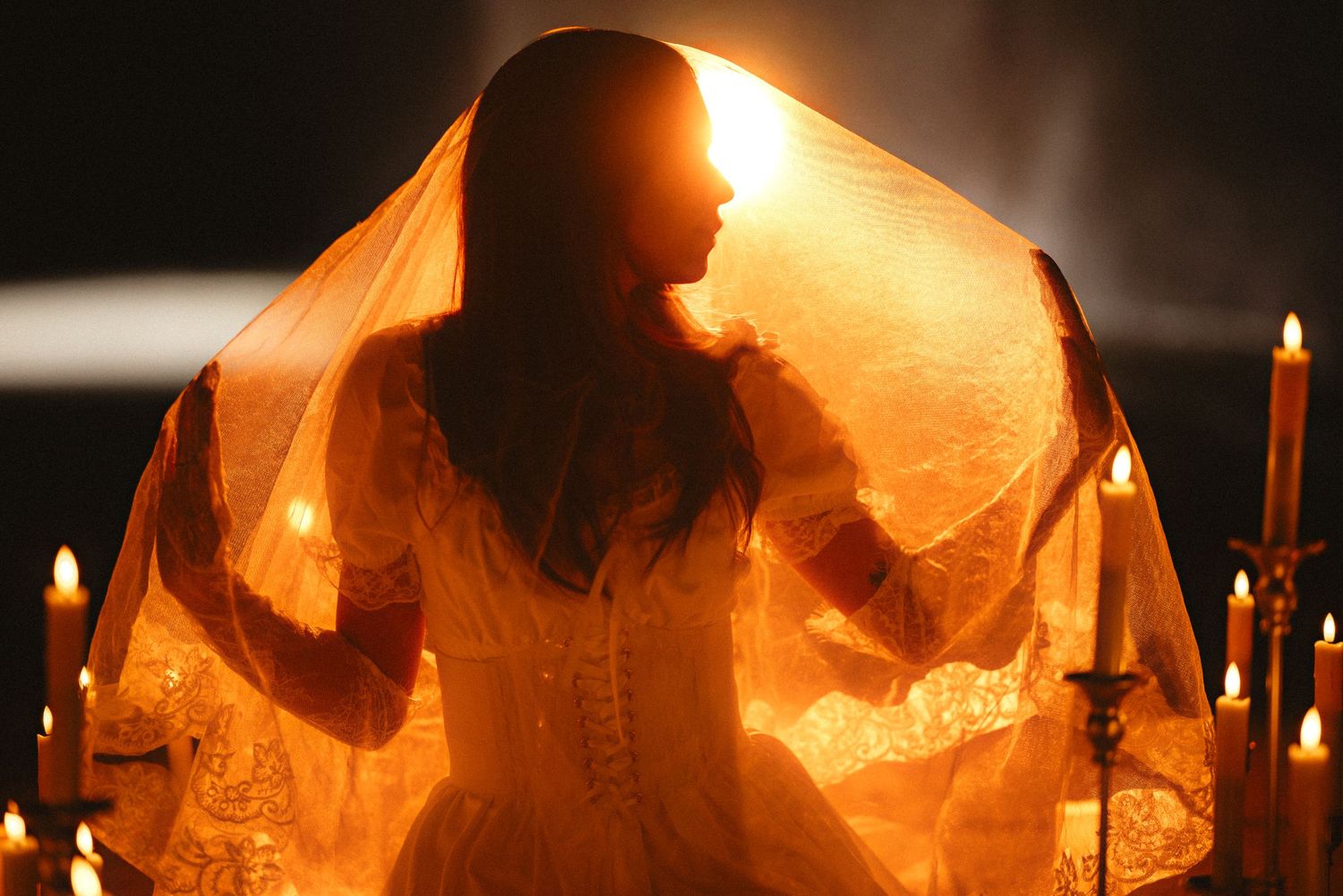 Silhouetted figures illuminated by warm candlelight create a mystical atmosphere during an evening ceremony.