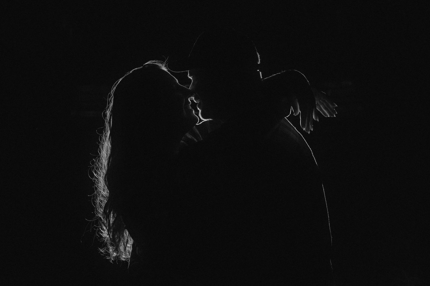 Artistic silhouette portrait with dramatic lighting against dark background.