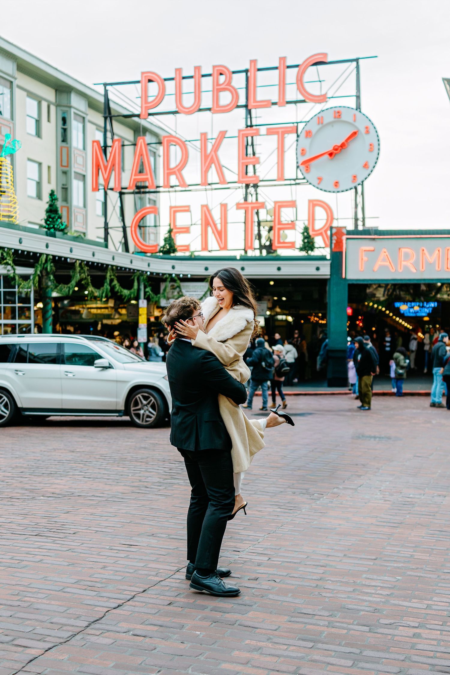 People gathered outside Pike Place Market in Seattle with iconic neon signs visible.