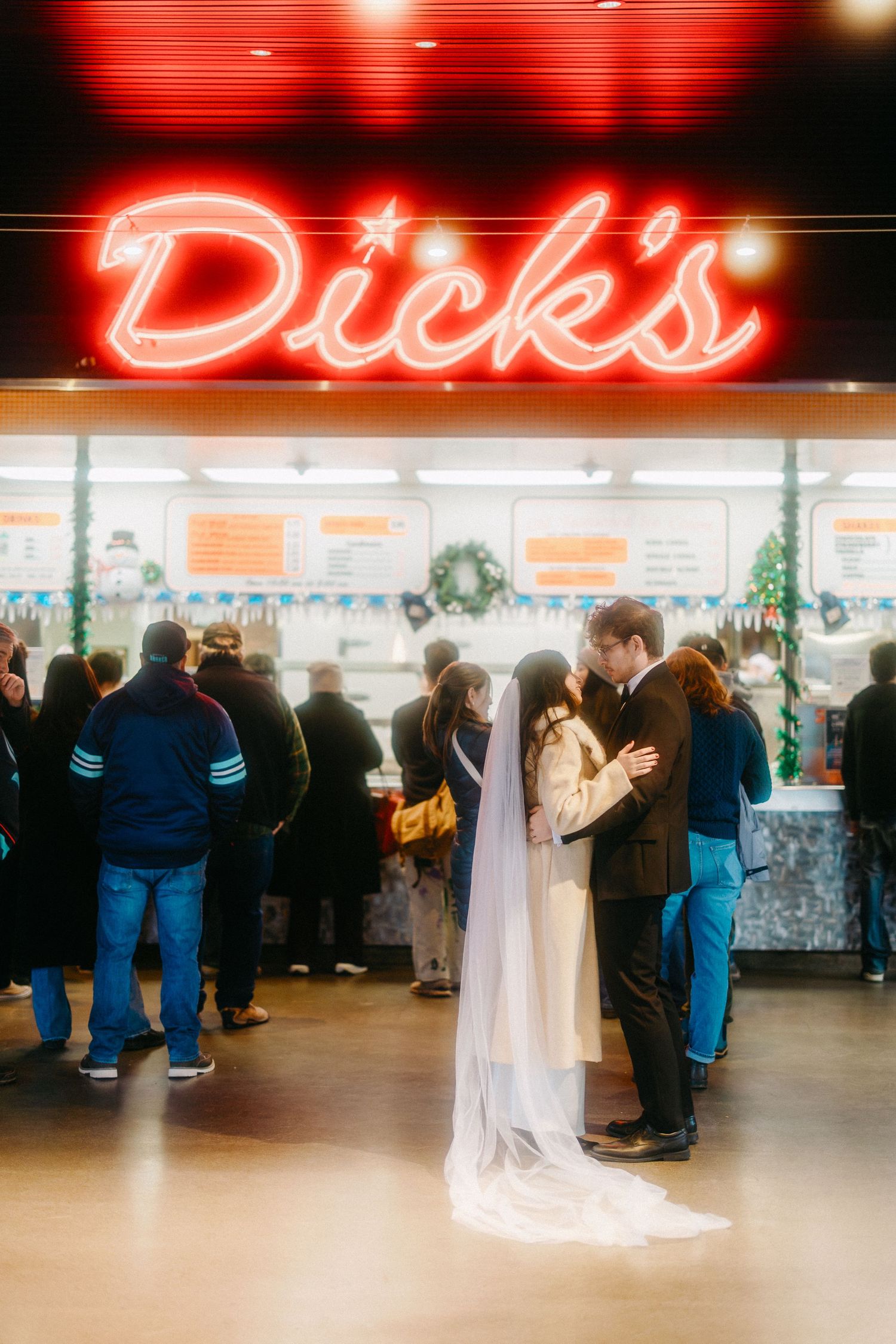 Wedding guests gather under red neon lighting at Dick's restaurant for an evening celebration.