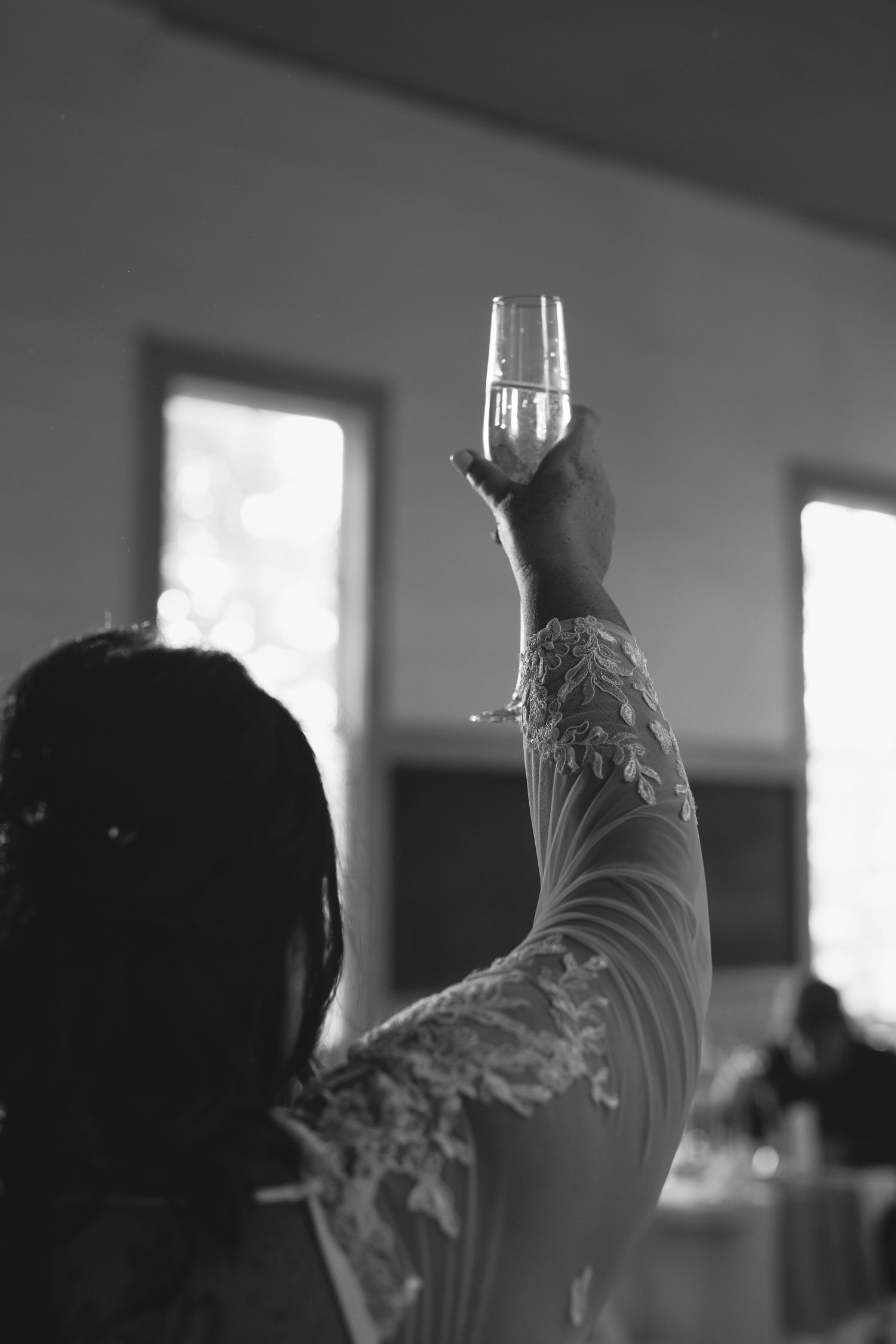Silhouette of hands raised in celebration against a bright window background in a dimly lit room.