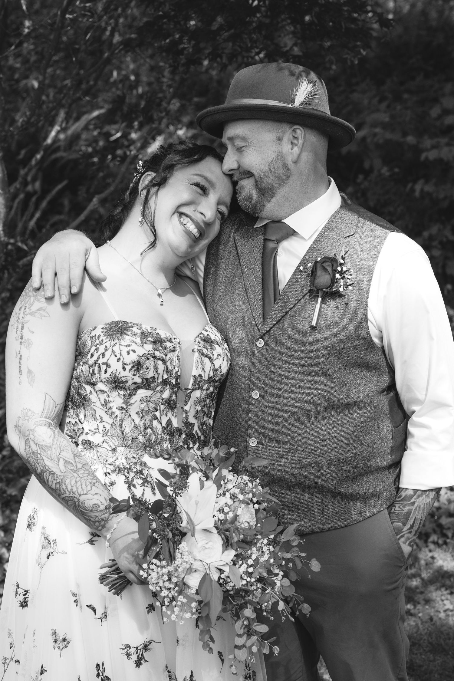 Black and white portrait of a couple in wedding attire with floral bouquet.
