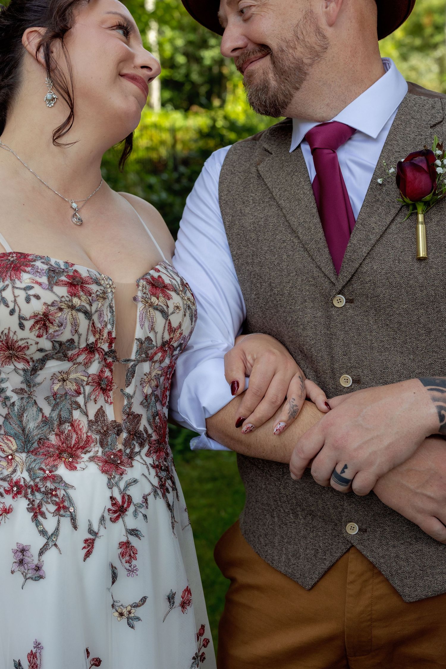 Detail shots of a couple's wedding attire showing floral dress and tweed vest with burgundy accents.