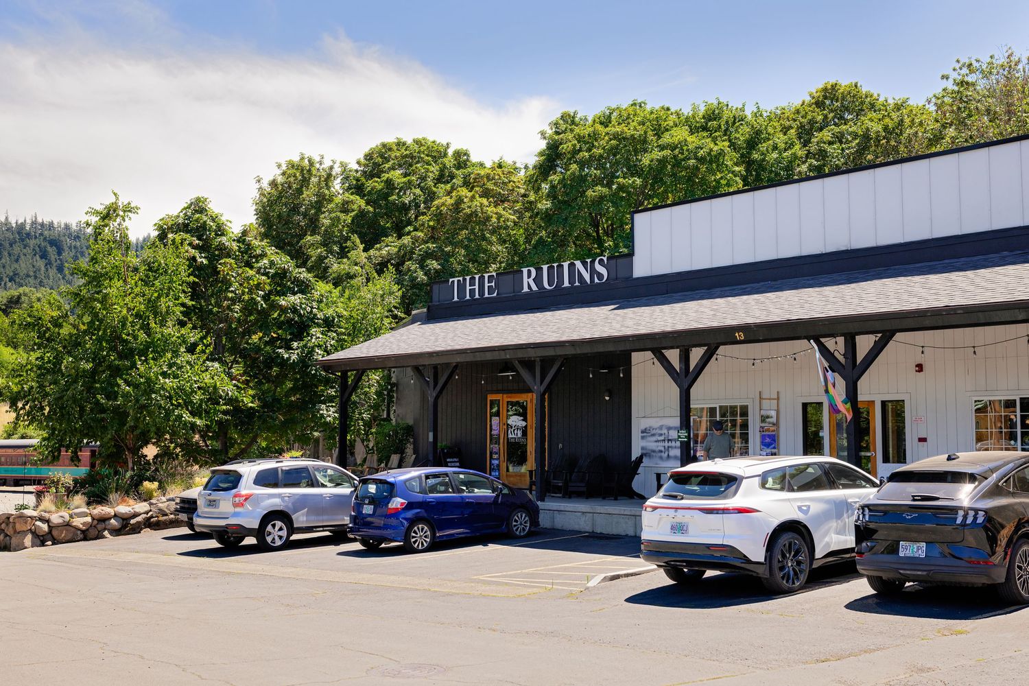 Exterior of The Ruins restaurant with parked cars in a wooded setting.