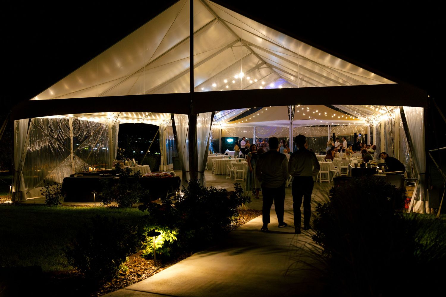 Panoramic view of illuminated outdoor event tents at night with ambient lighting creating a warm atmosphere.