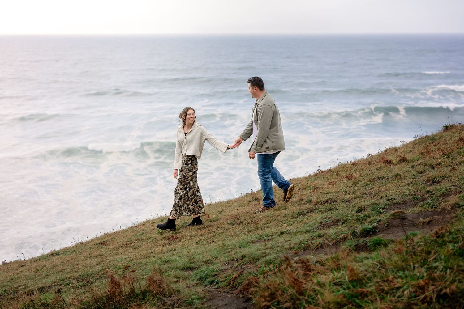 A couple shares an intimate moment on a scenic coastal cliff overlooking the ocean.