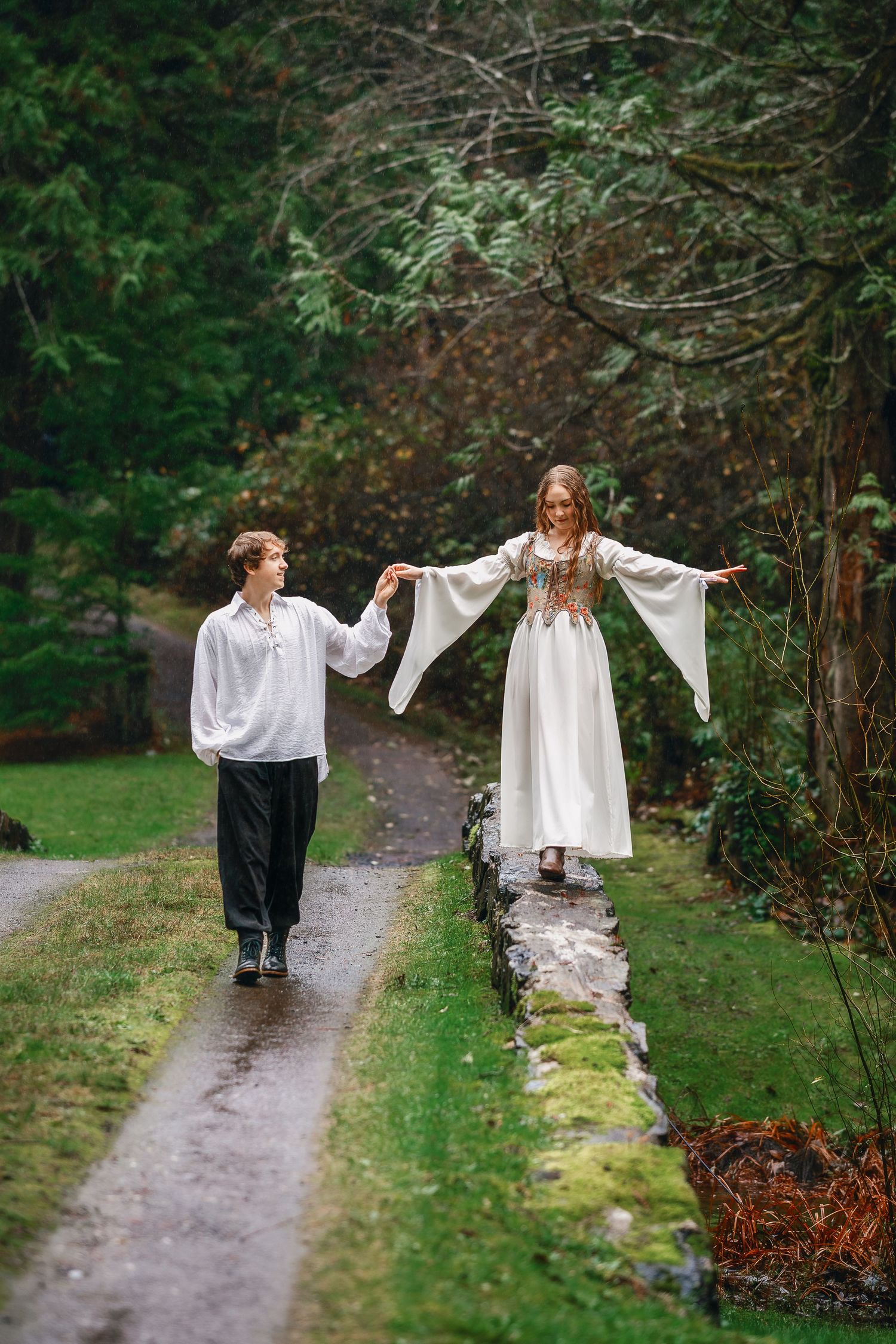 Figures in white clothing walk along a misty forest path surrounded by greenery.