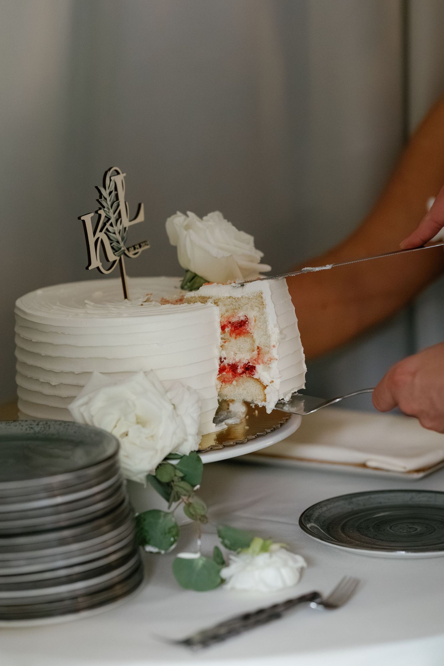 Slices of white wedding cake being served on elegant gray plates at a reception.