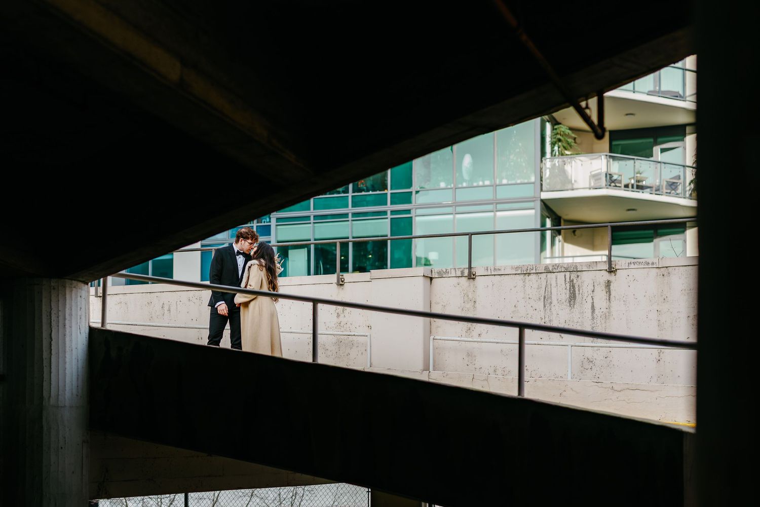 Person standing on concrete walkway viewed through architectural framing.