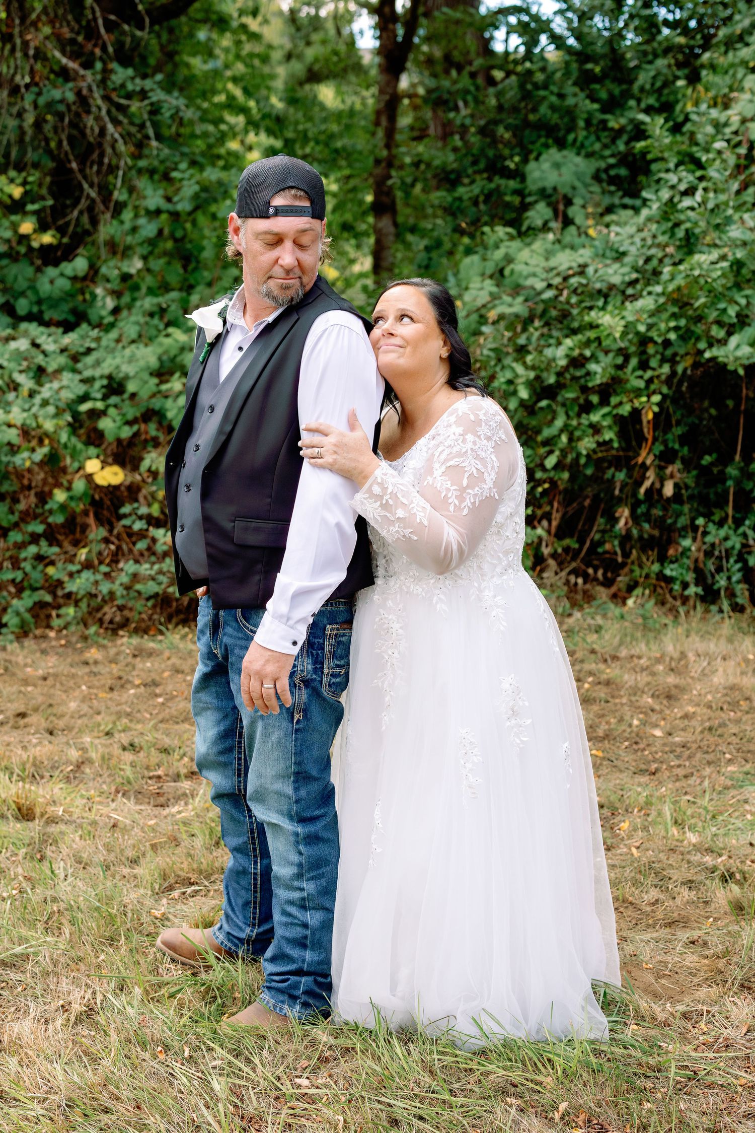 A romantic wedding portrait showing a couple in casual western style with the bride in a lace dress.